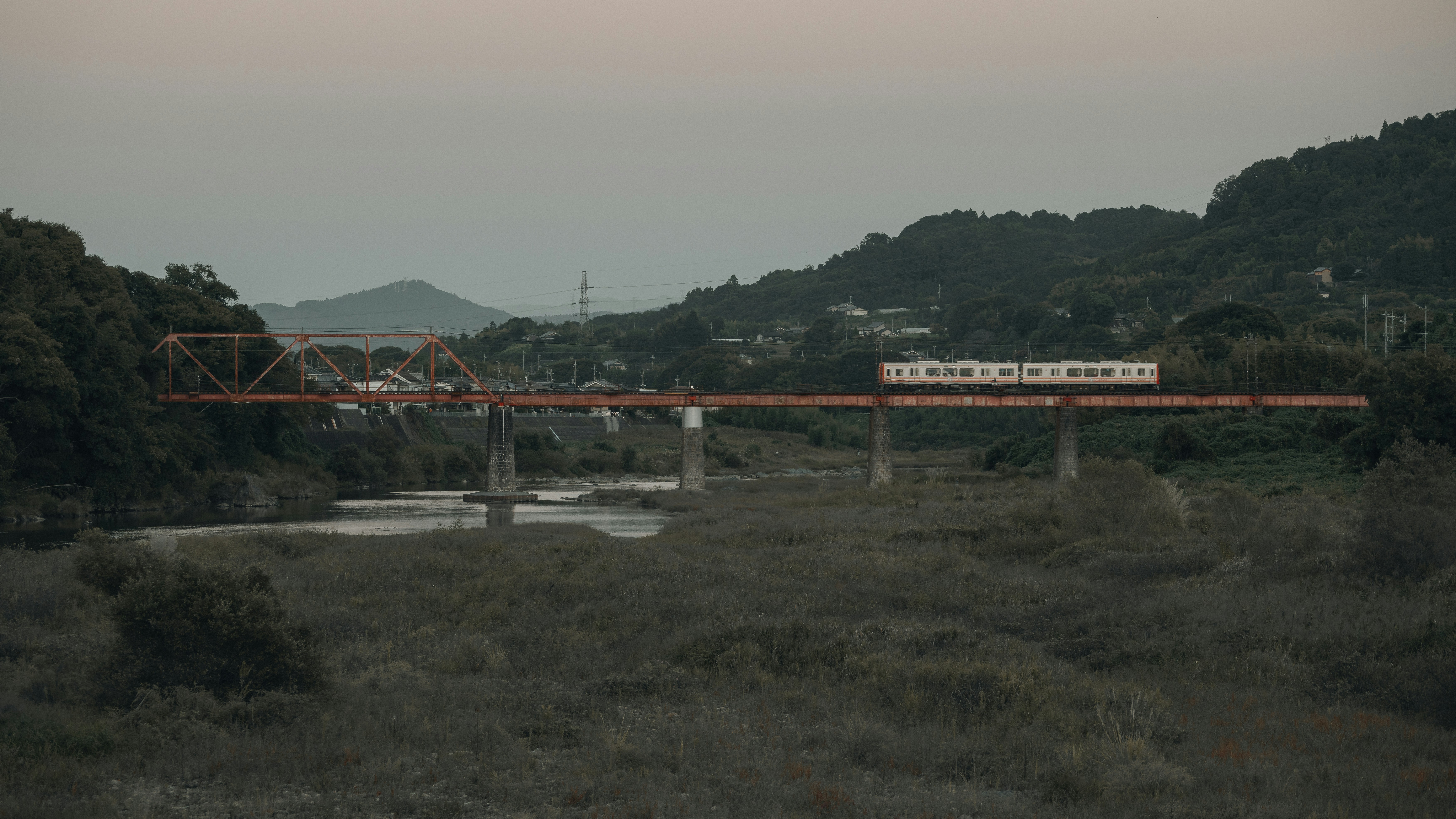 Red bridge over a river with hills background