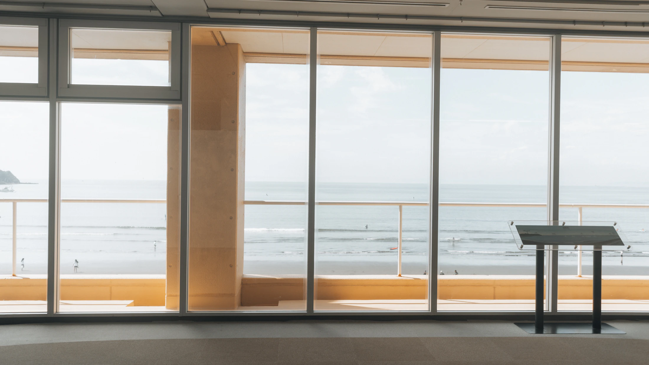 Floor to ceiling windows framing the beach and open ocean