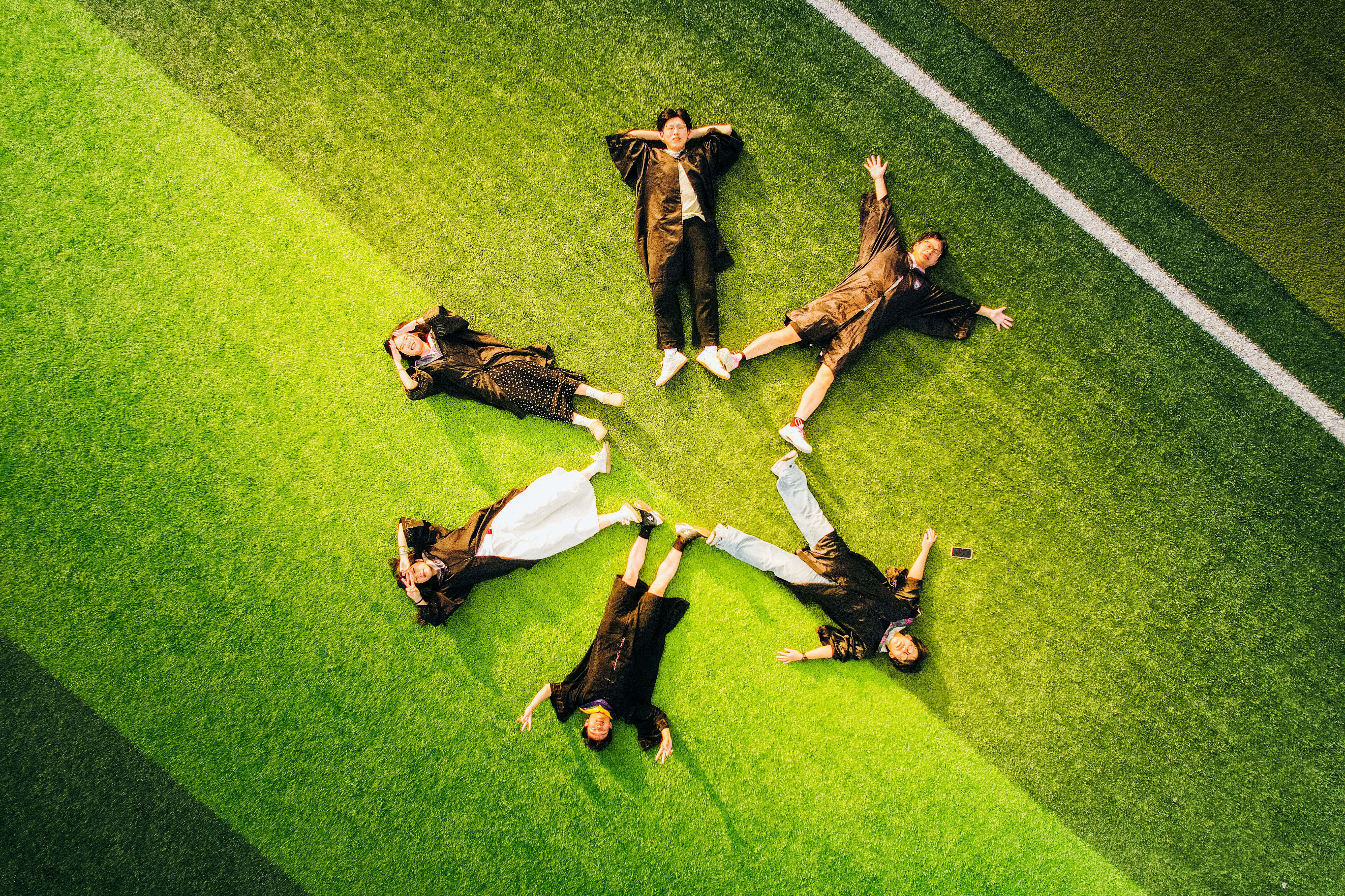People lying in a circle on green grass