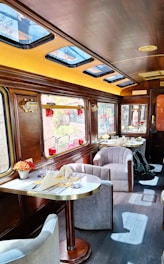 Luxurious train carriage interior with dining tables and seating.