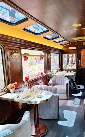 Luxurious train carriage interior with dining tables and seating.