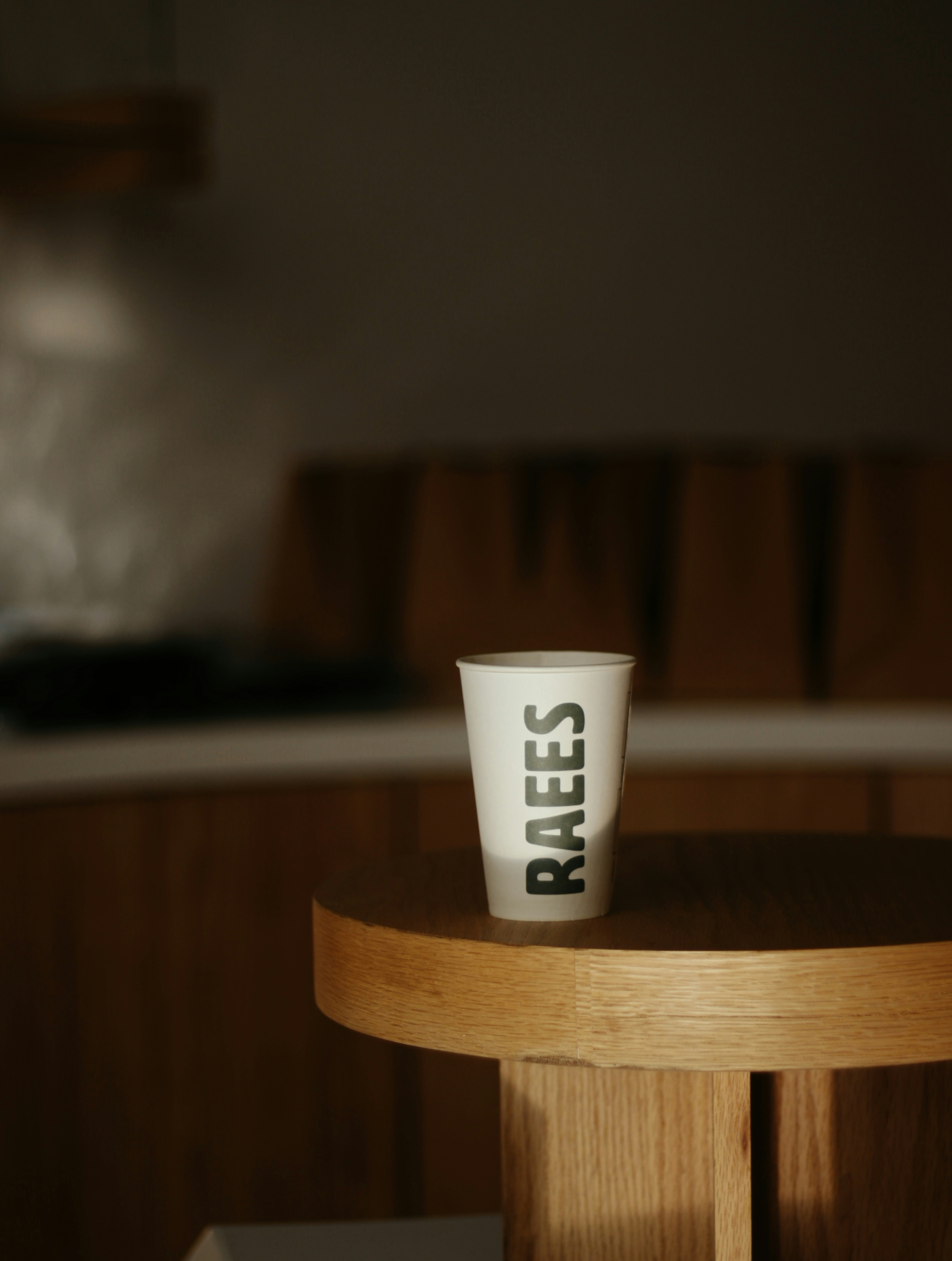 White paper cup with "raees" logo on table