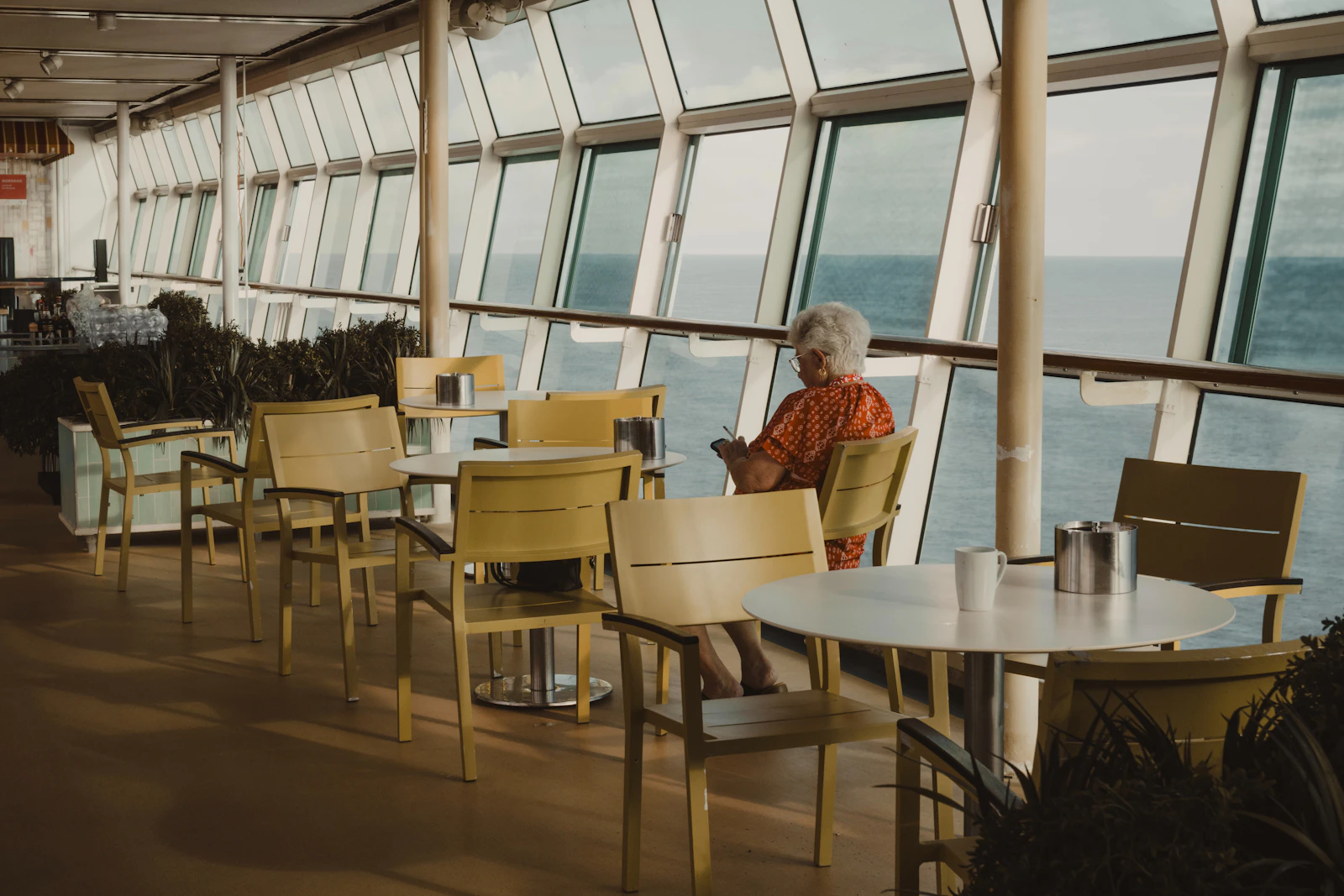 Passagère assise près d'un hublot à bord d'un navire de croisière, en train de lire
