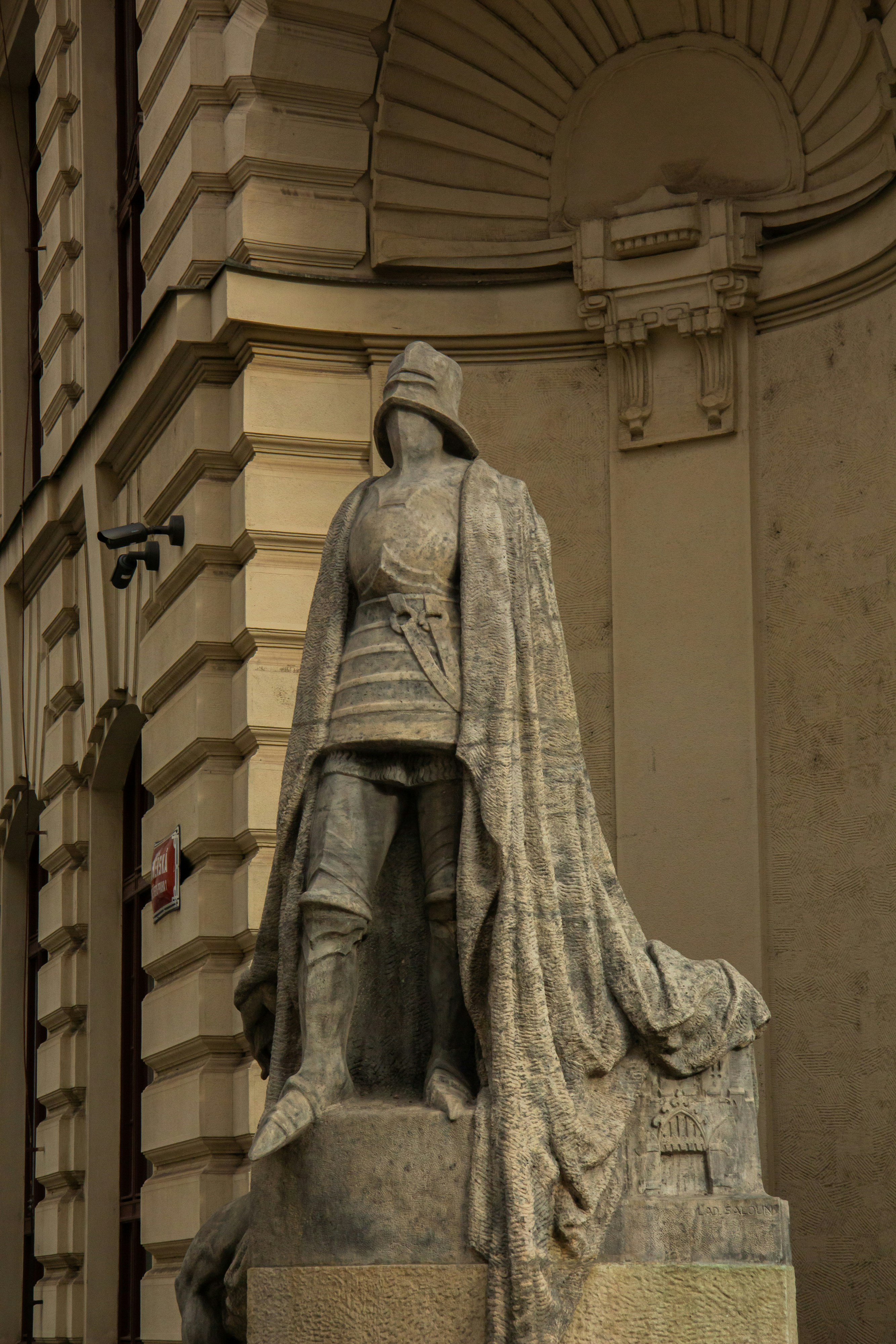 Stone statue of a man in armor with a cloak.