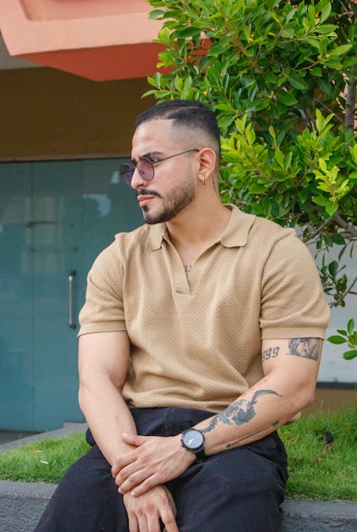 Man with tattoos wearing polo T-Shirt & sunglasses.