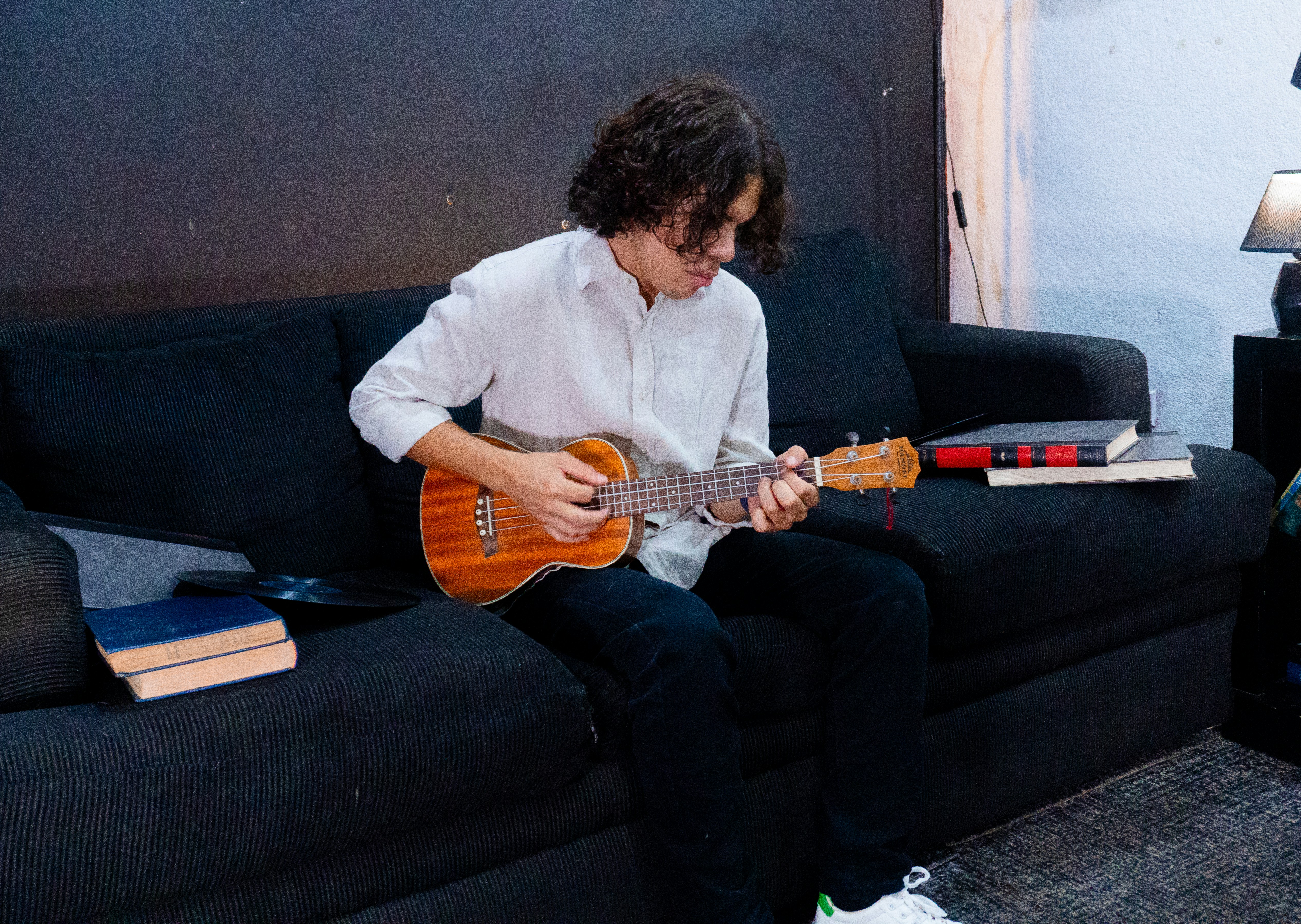 Young boy playing ukulele on a couch.