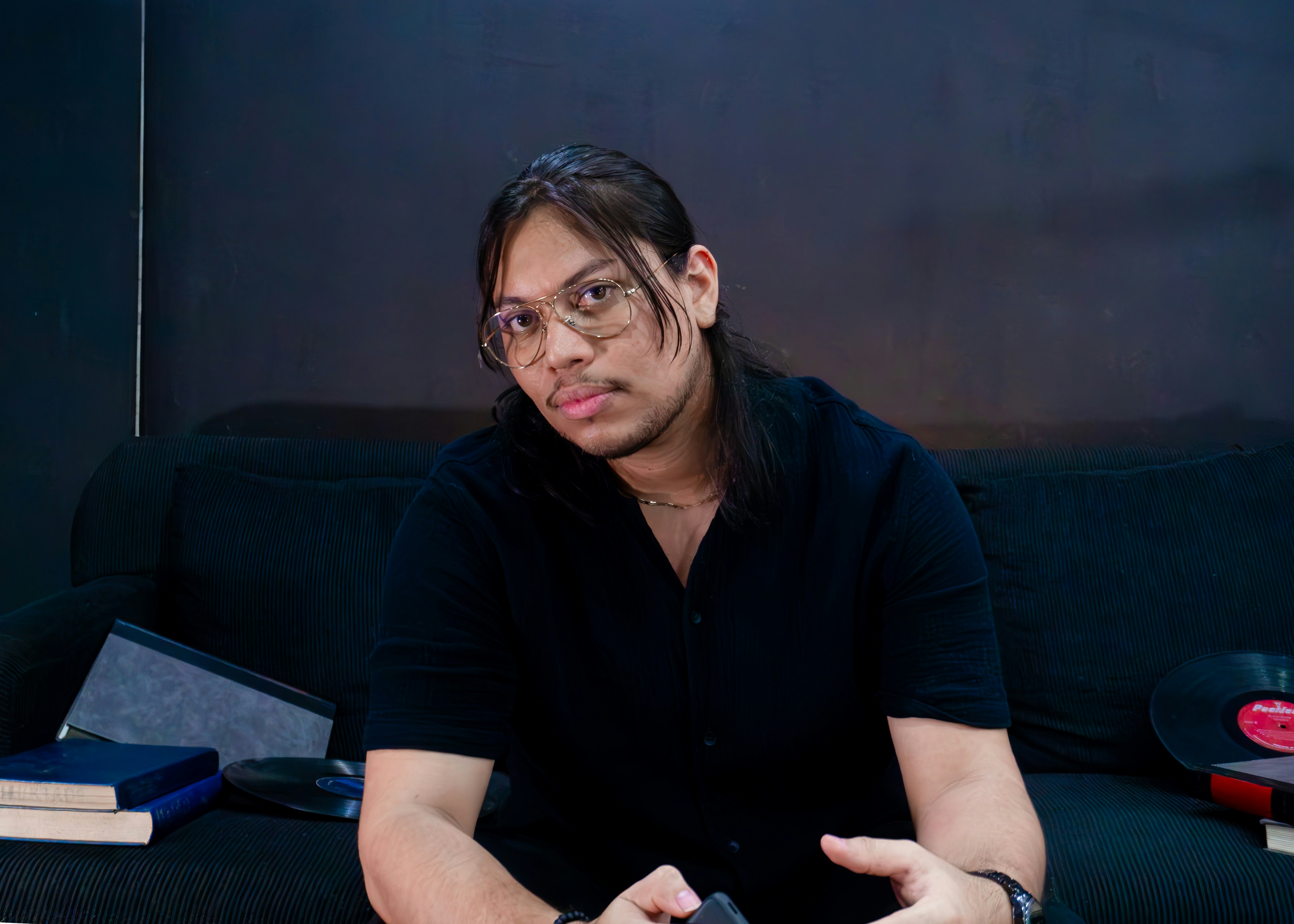 Hombre con gafas y pelo largo sentado en el sofá. foto – Imagen de ...