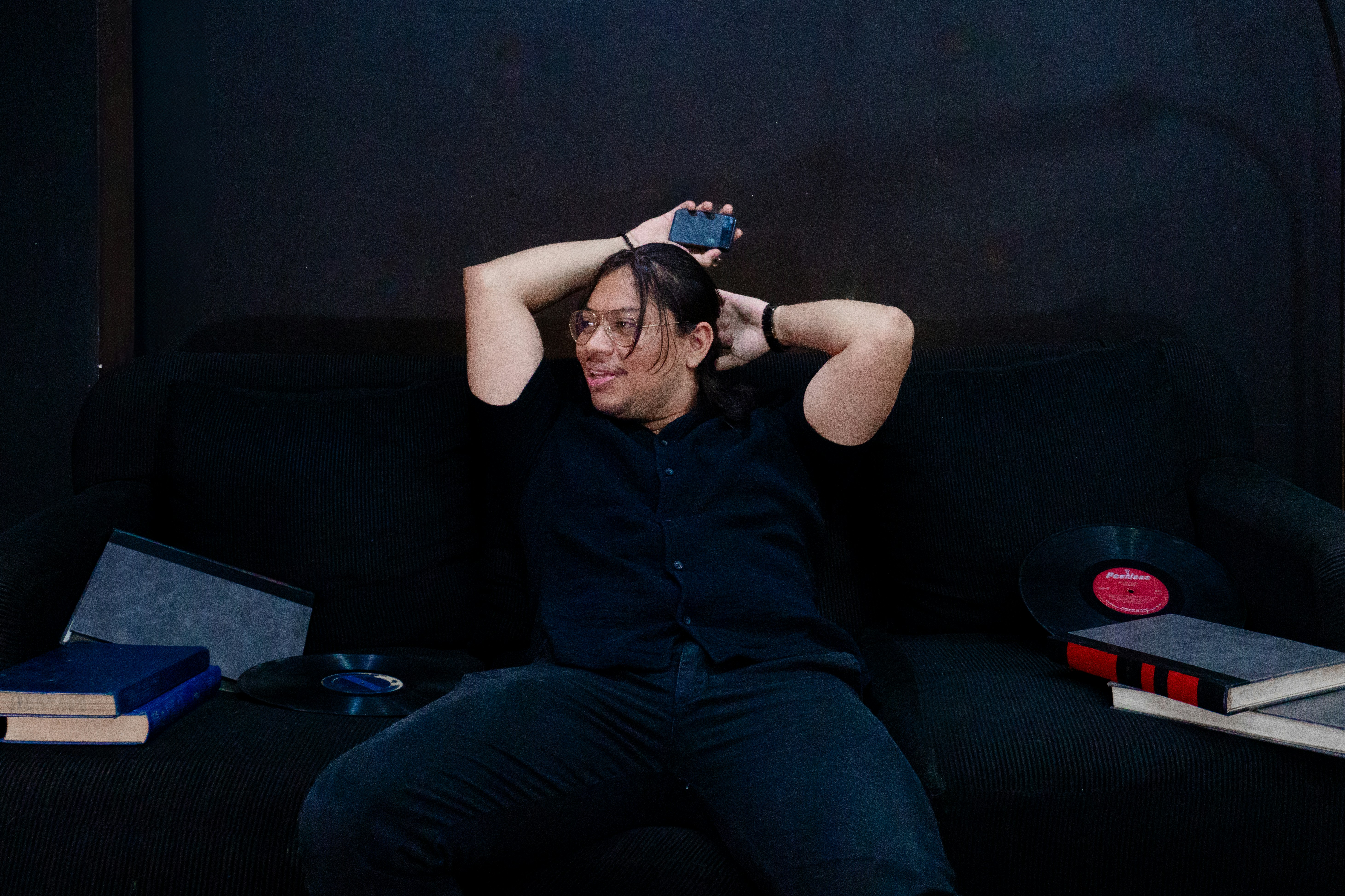 Person sitting on a couch with books and record.