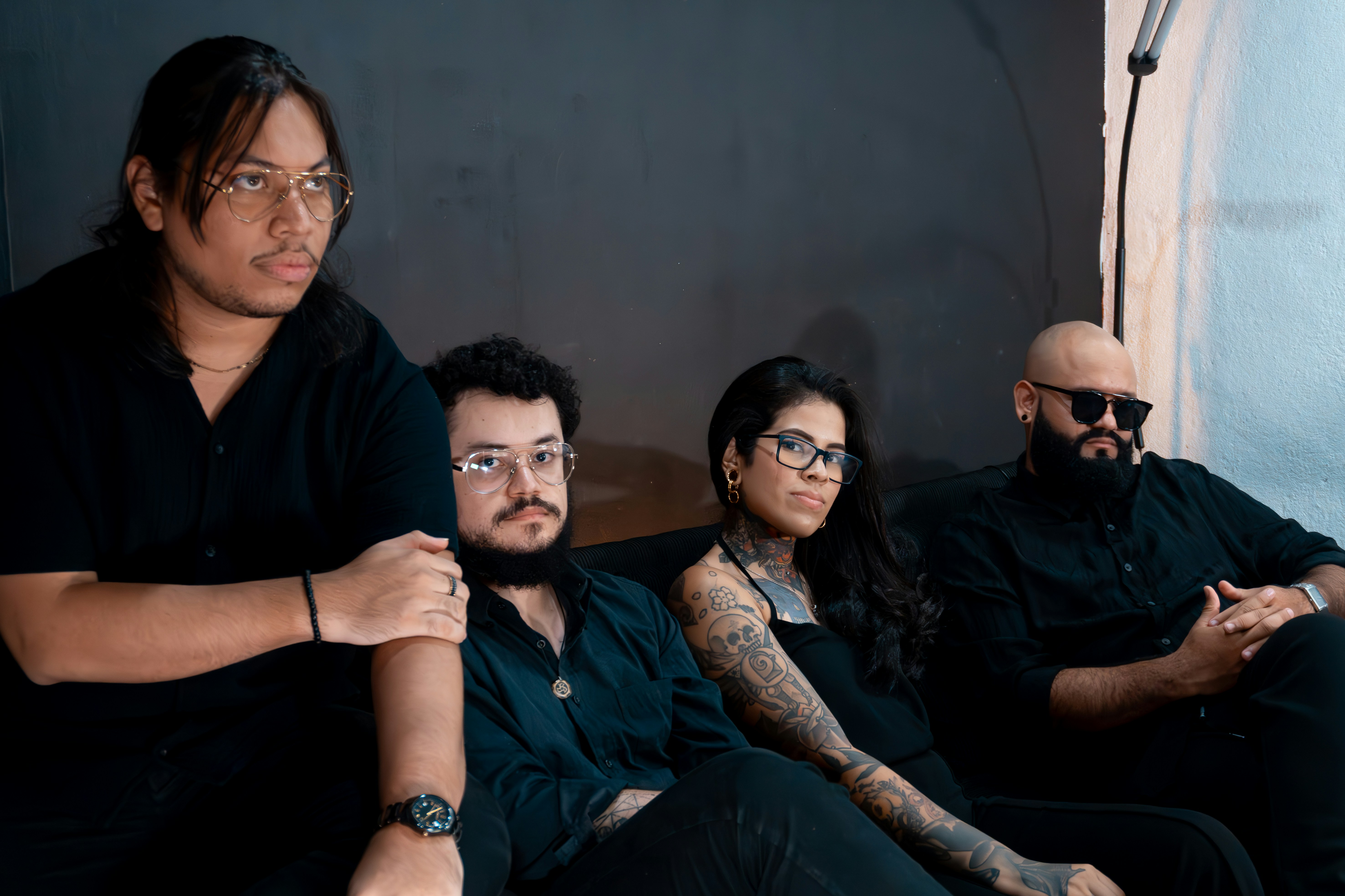Four people in black clothing sitting on a couch