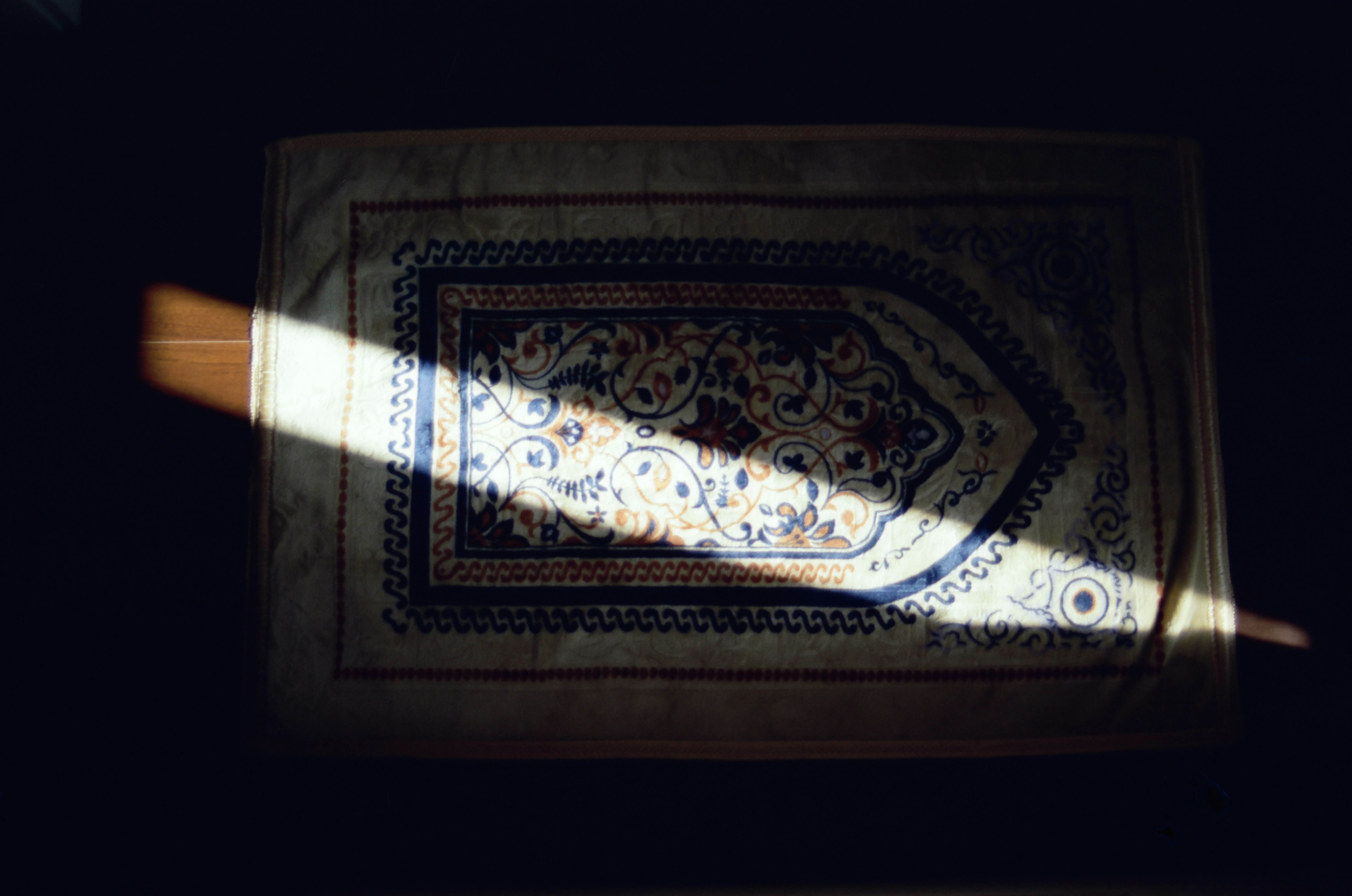 A prayer rug illuminated by a shaft of light.