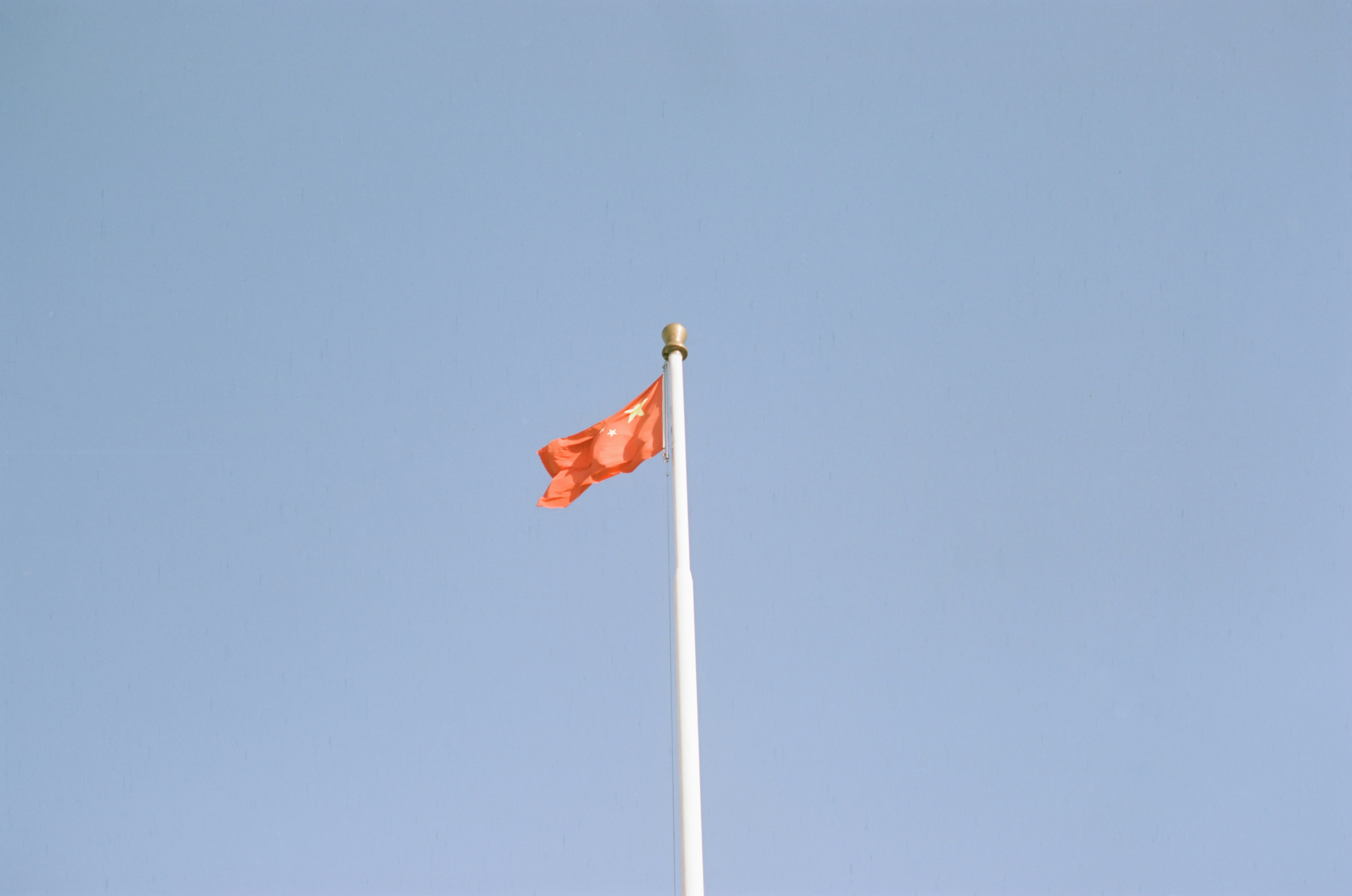 Orange flag waving on a flagpole against clear sky
