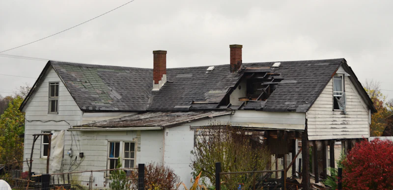 House with severe storm roof damage needing emergency tarping