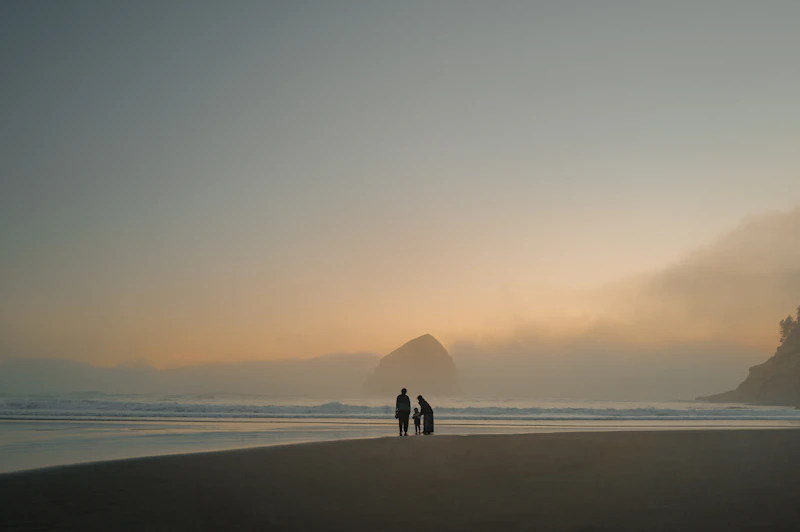 Family walking together on a foggy beach at sunset