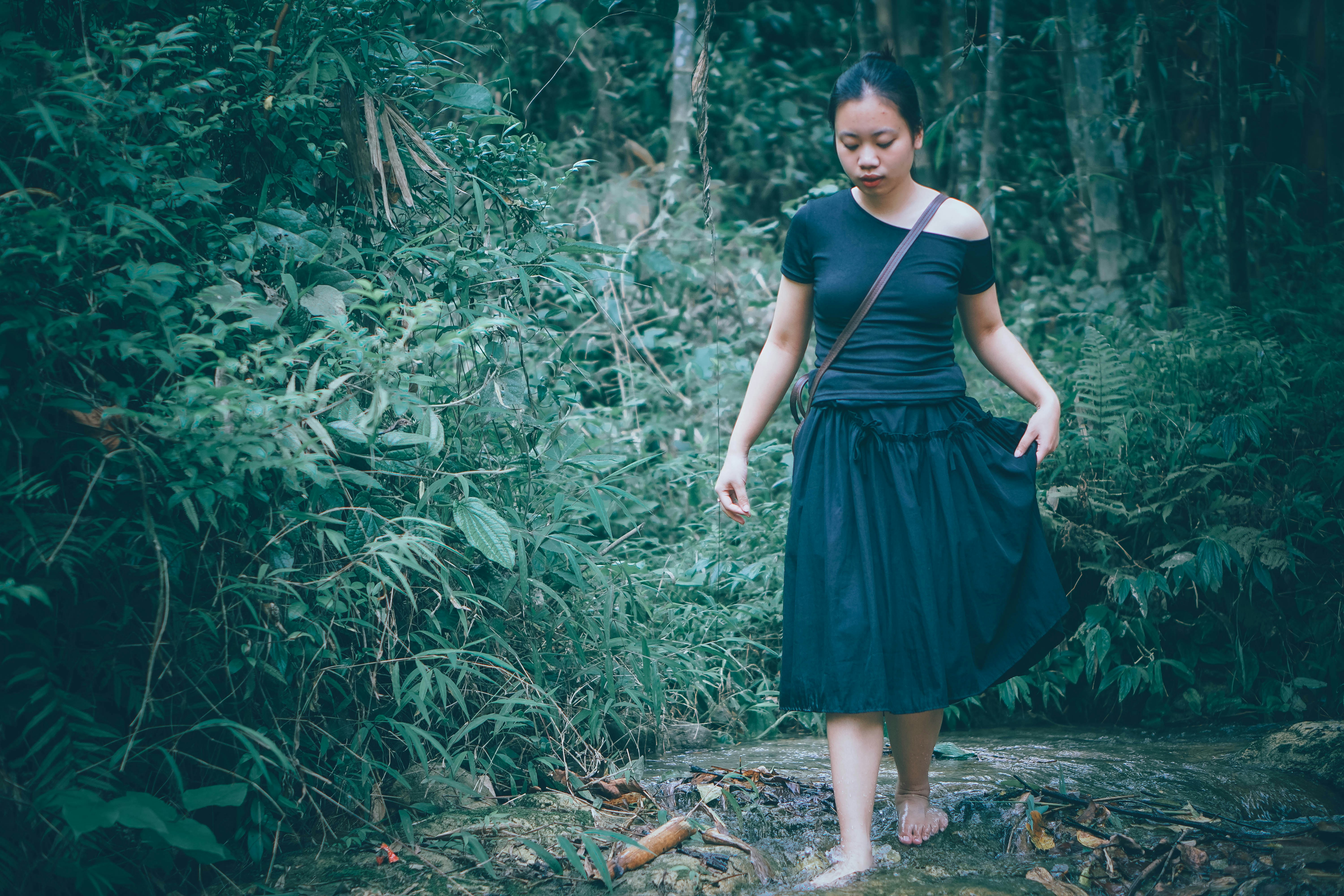 Woman walking barefoot through a lush green forest.