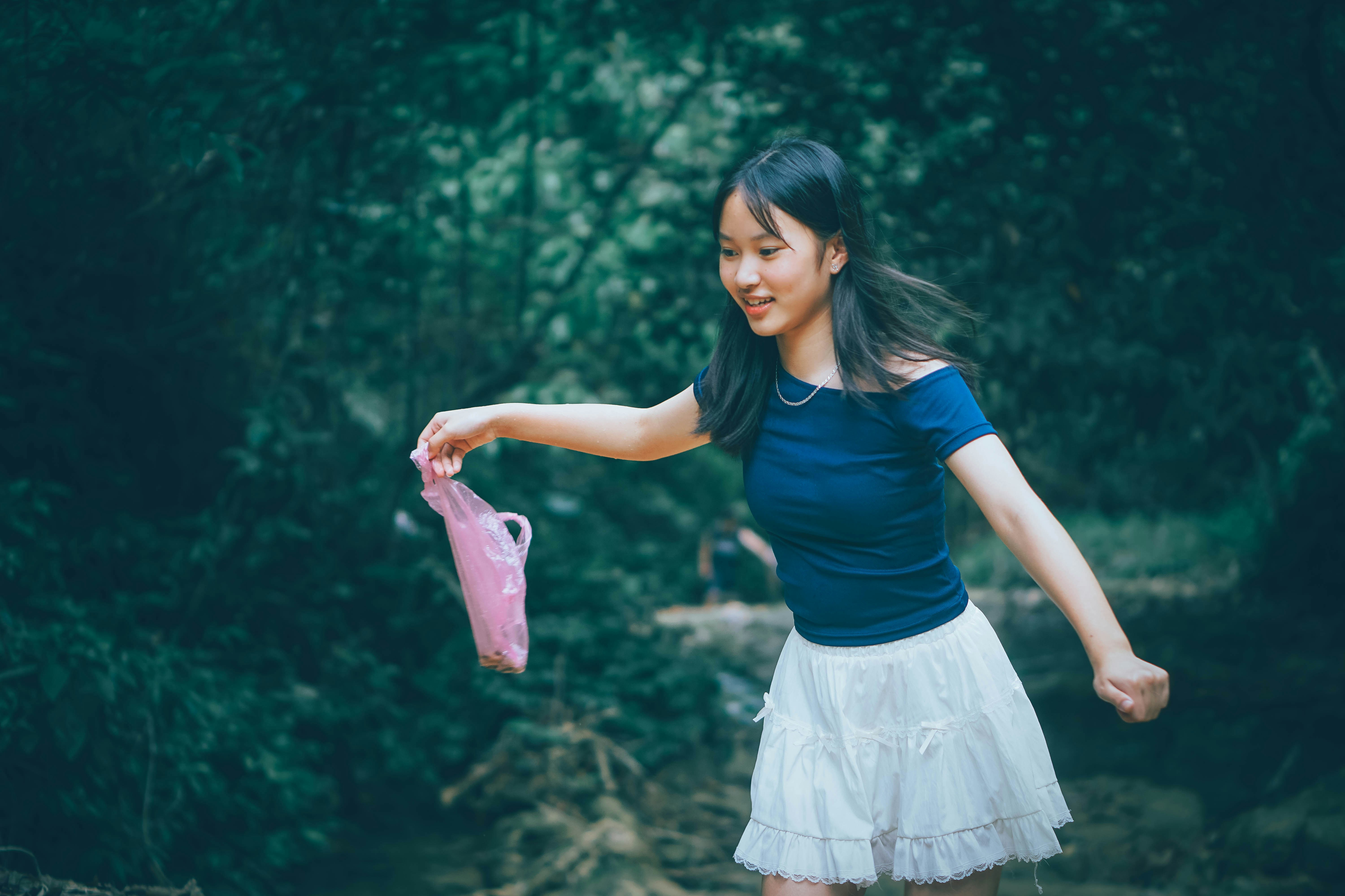 Young woman holding a pink bag in a forest.