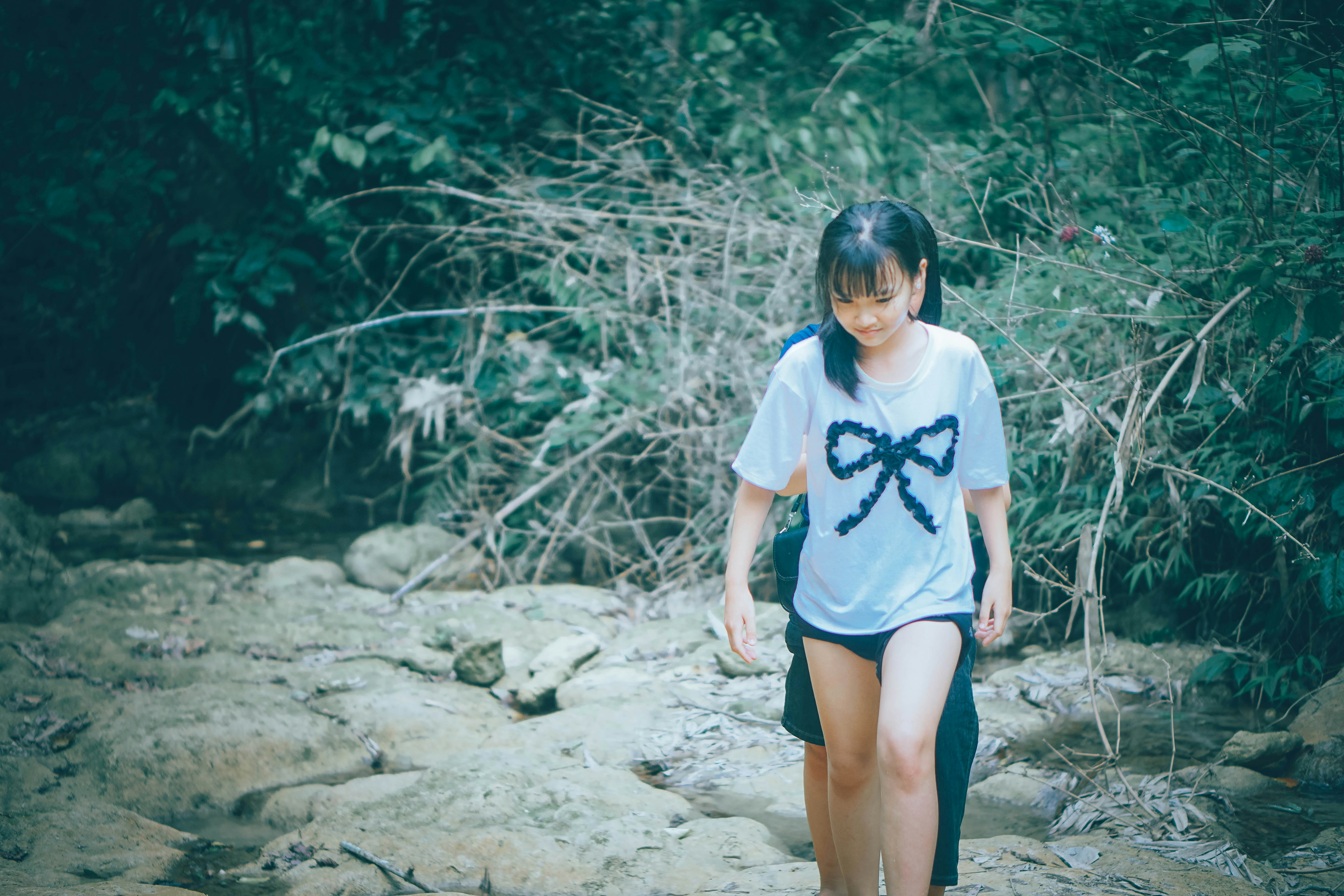 Young woman walks through a rocky stream.