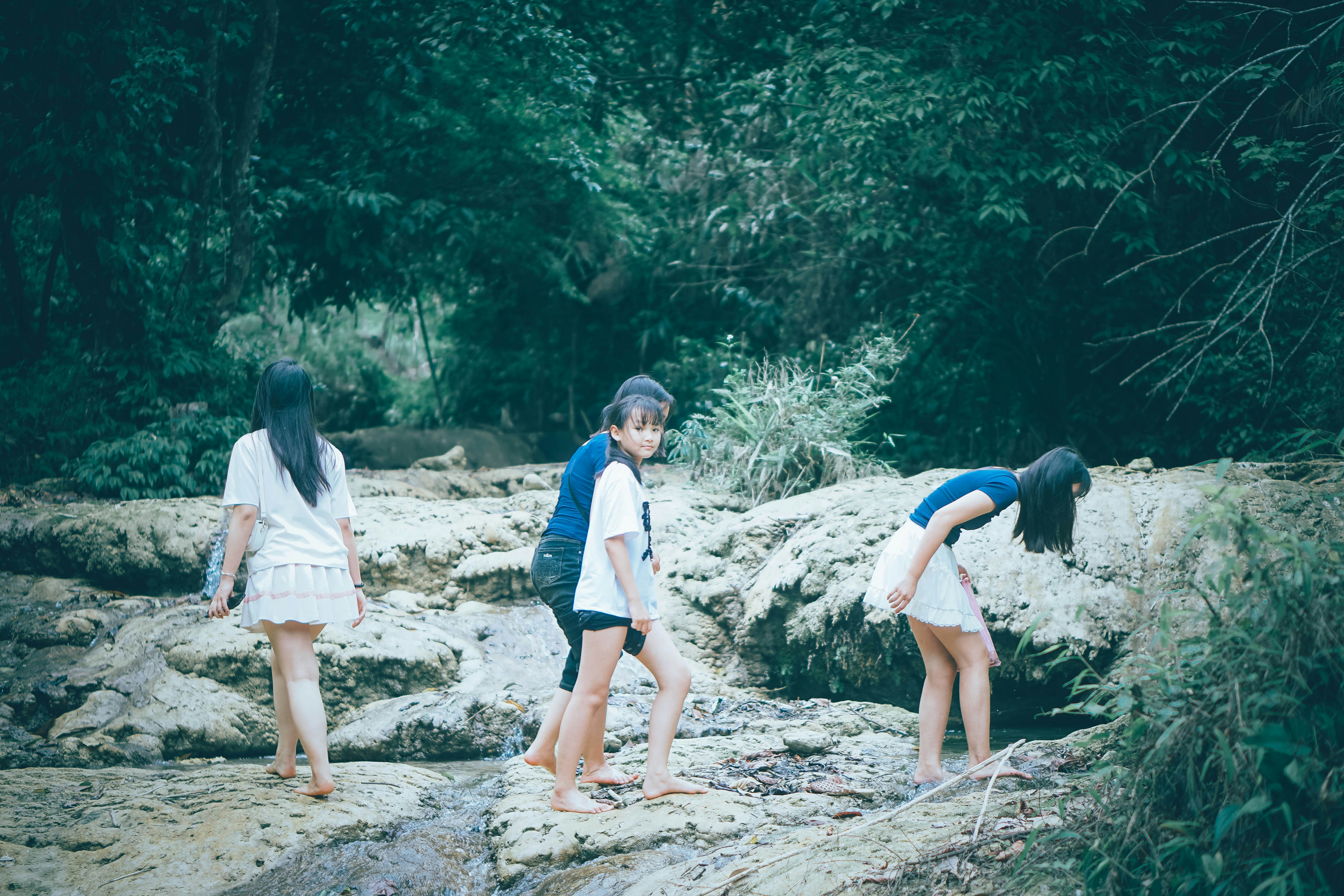 Three girls walk by a rocky stream.