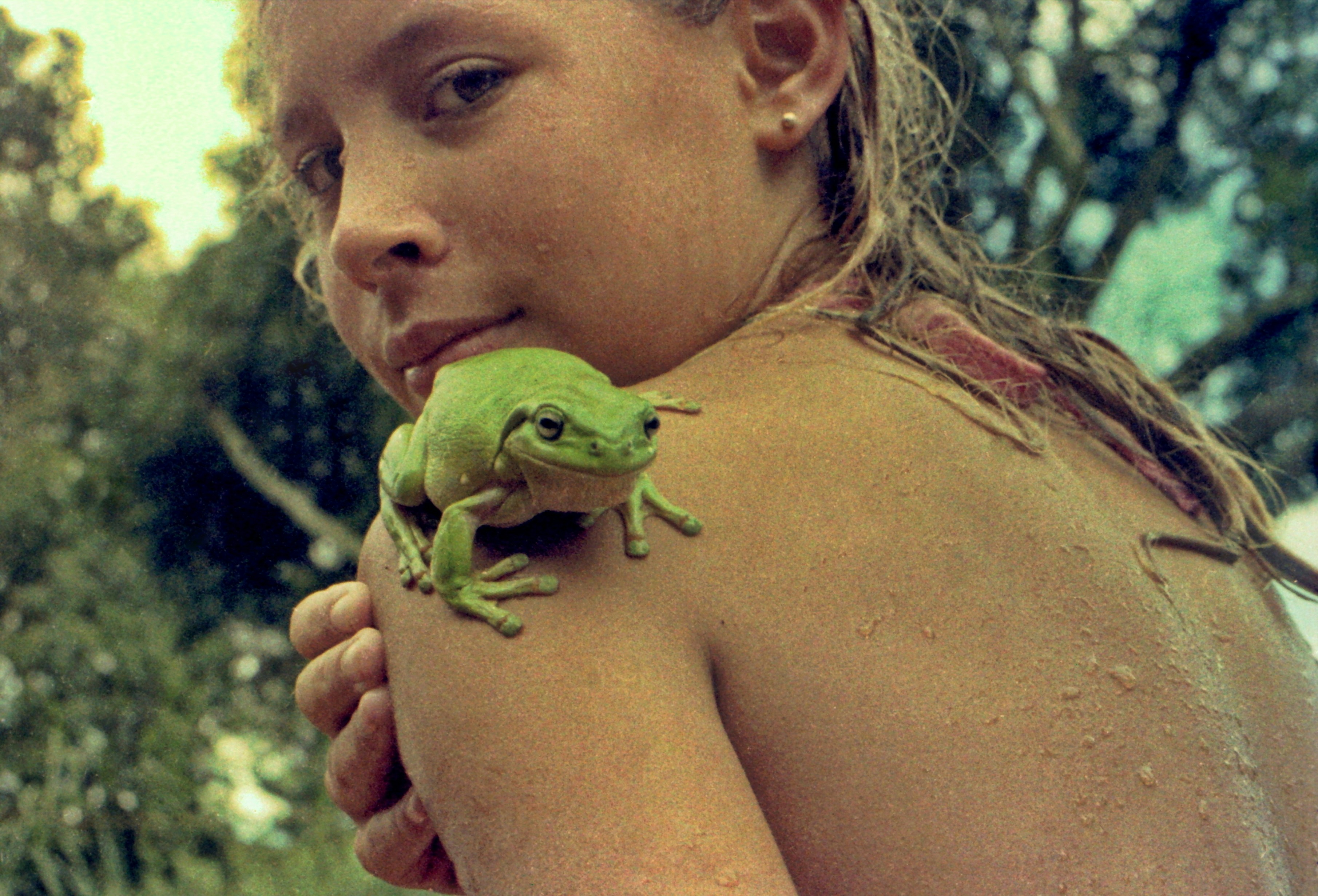 Une jeune fille avec une grenouille verte sur son épaule.