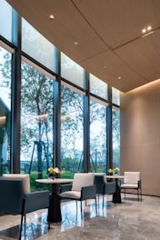 Modern seating area with large windows and trees outside.