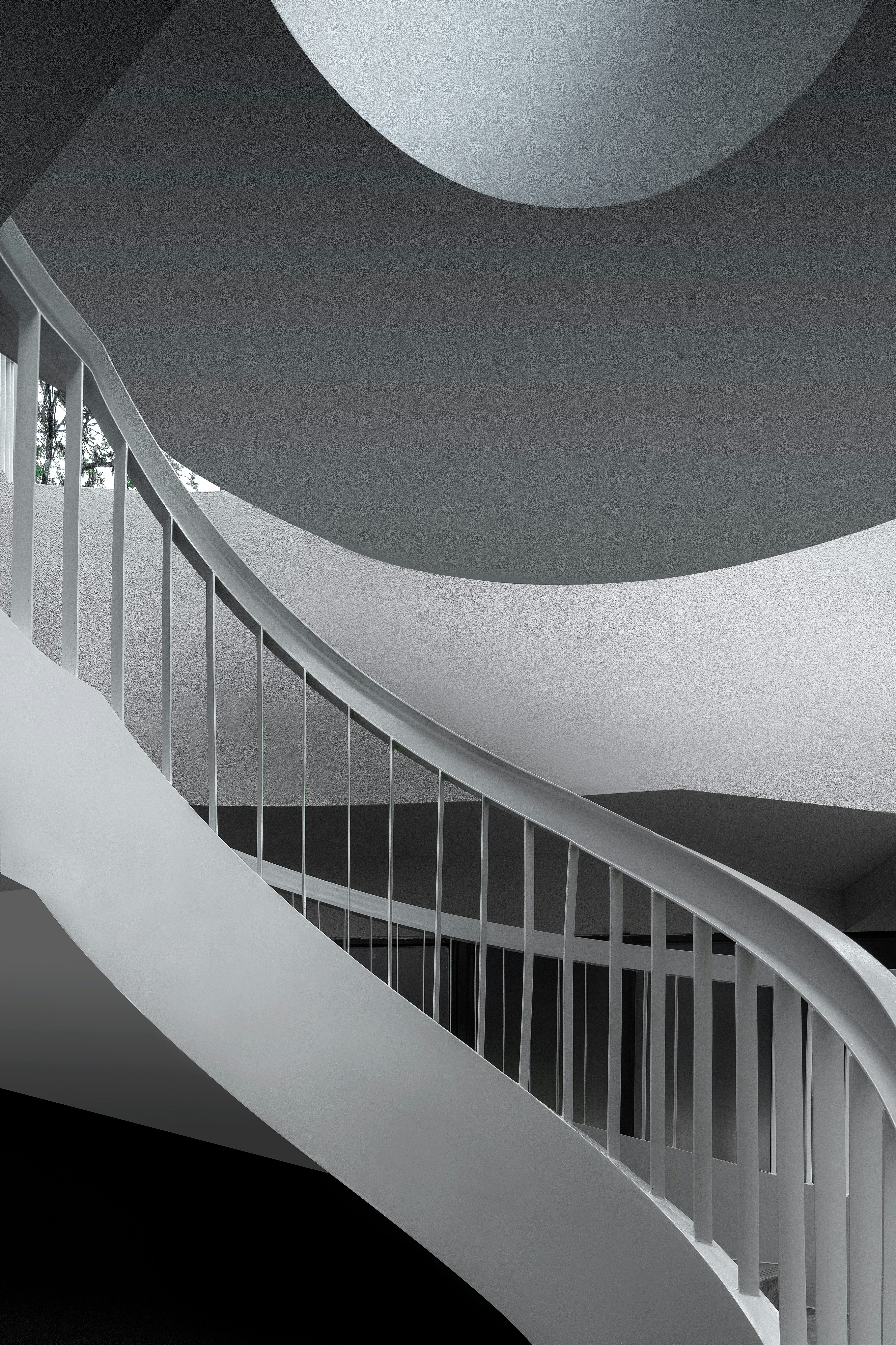 Curving white staircase with railing against dark background