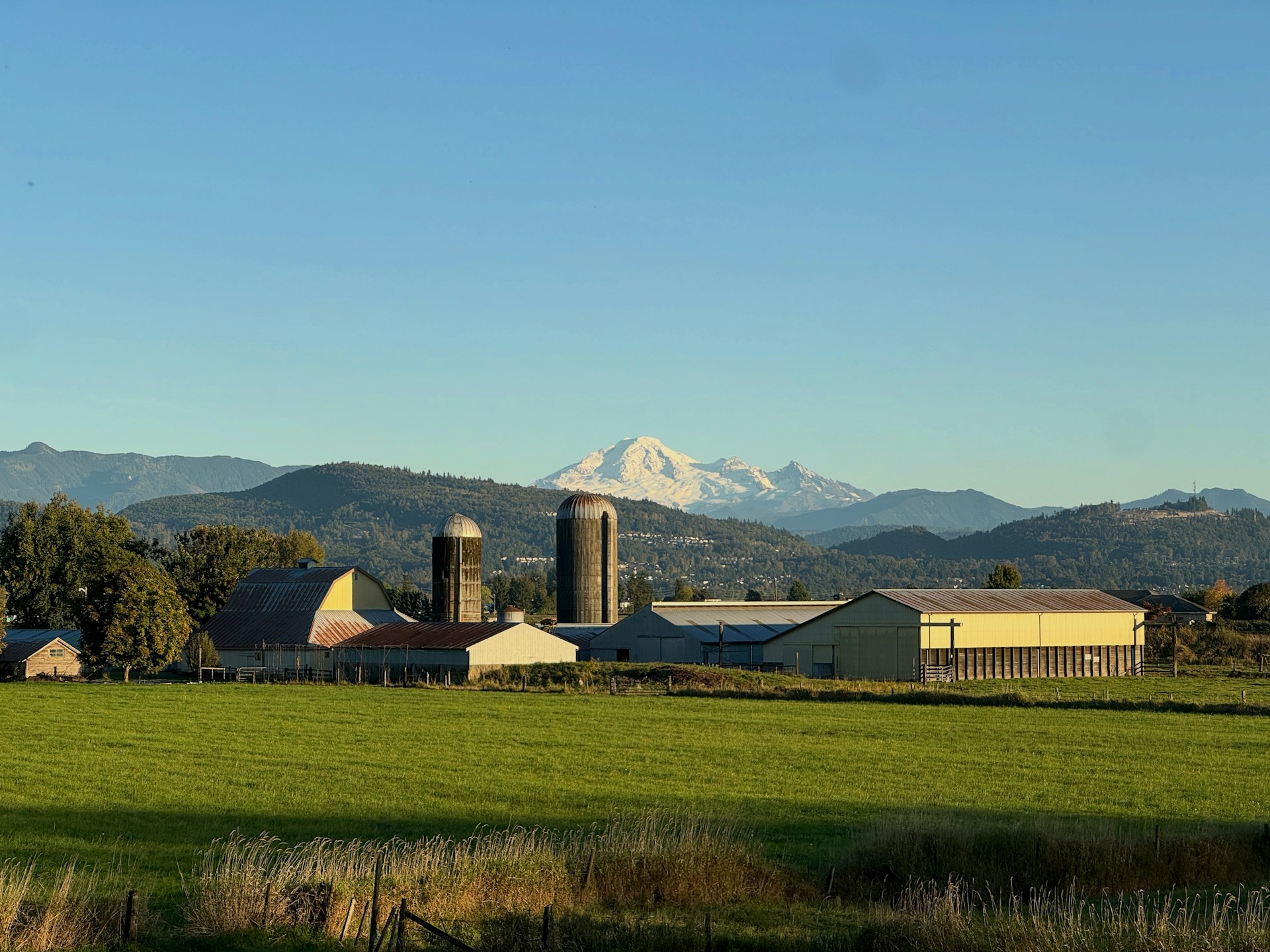 Farm buildings with silos and distant snow-capped mountains.