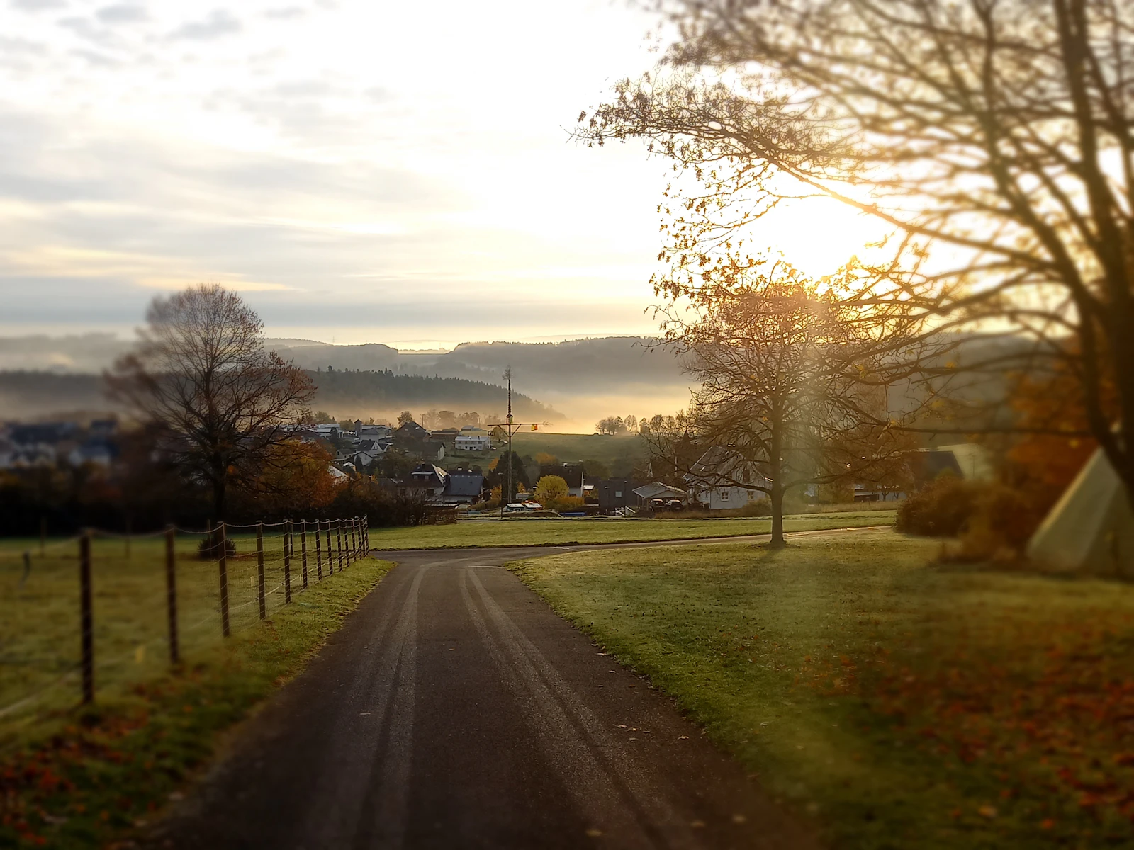 A rural road leading toward a village at sunrise