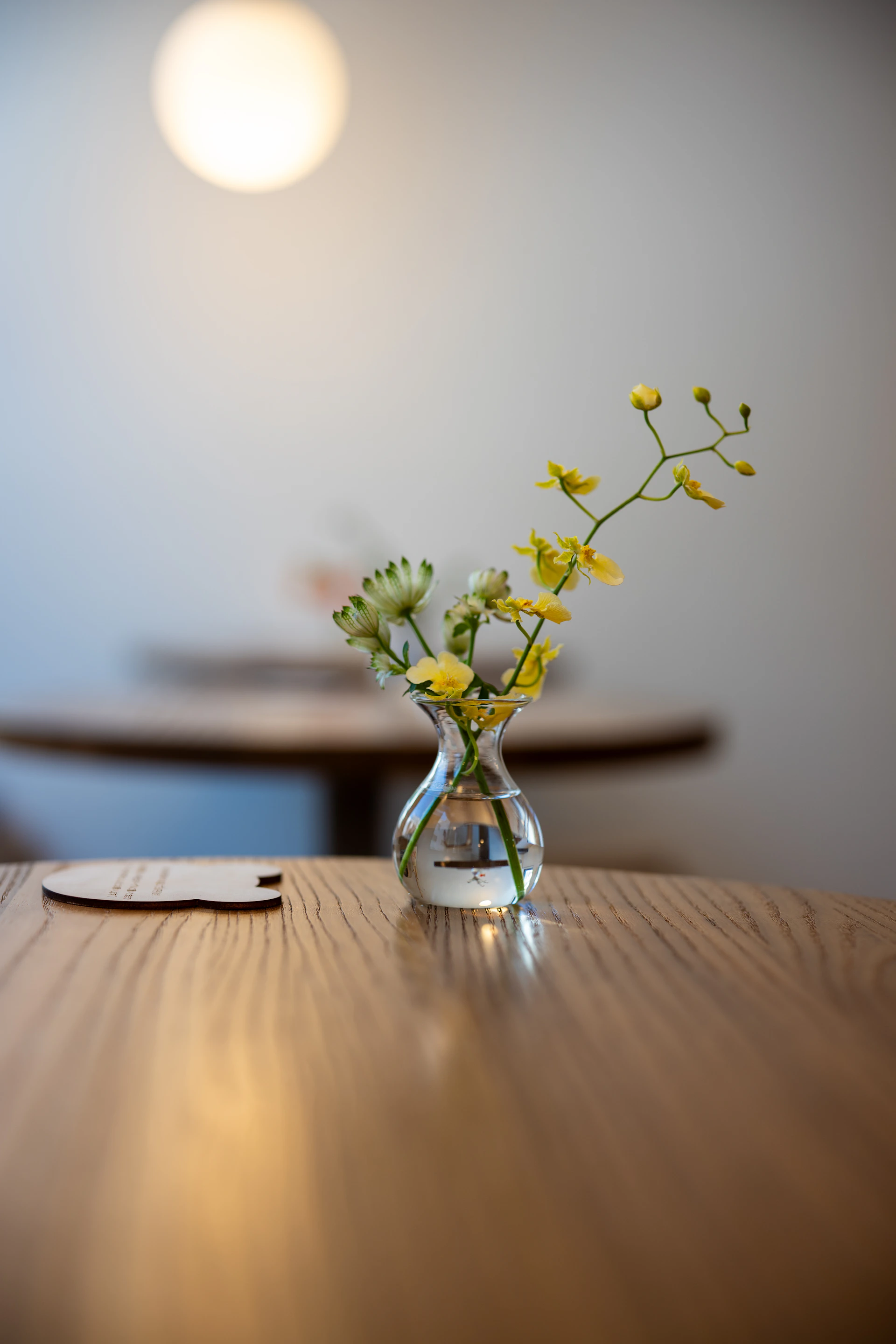 Small vase with yellow flowers on a wooden table