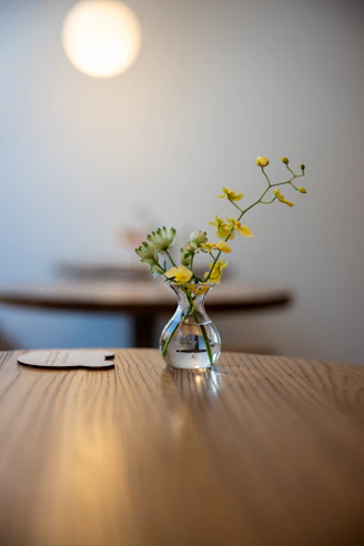 Small vase with yellow flowers on a wooden table