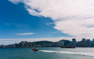 Boats sail on the water with city skyline background.