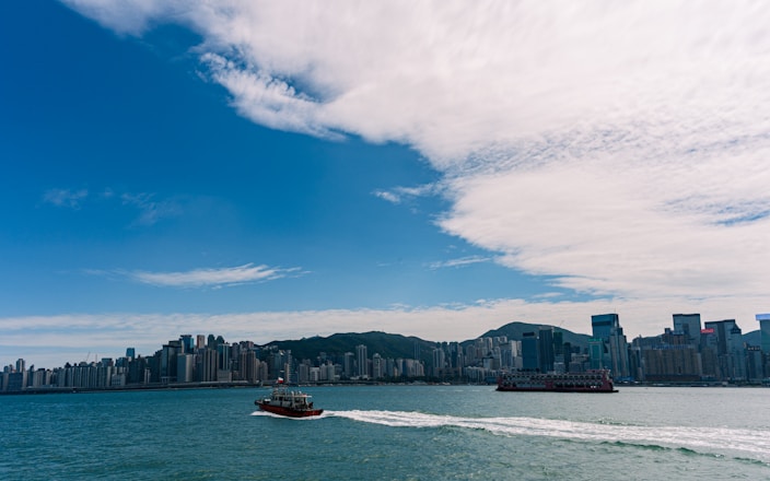 Boats sail on the water with city skyline background.