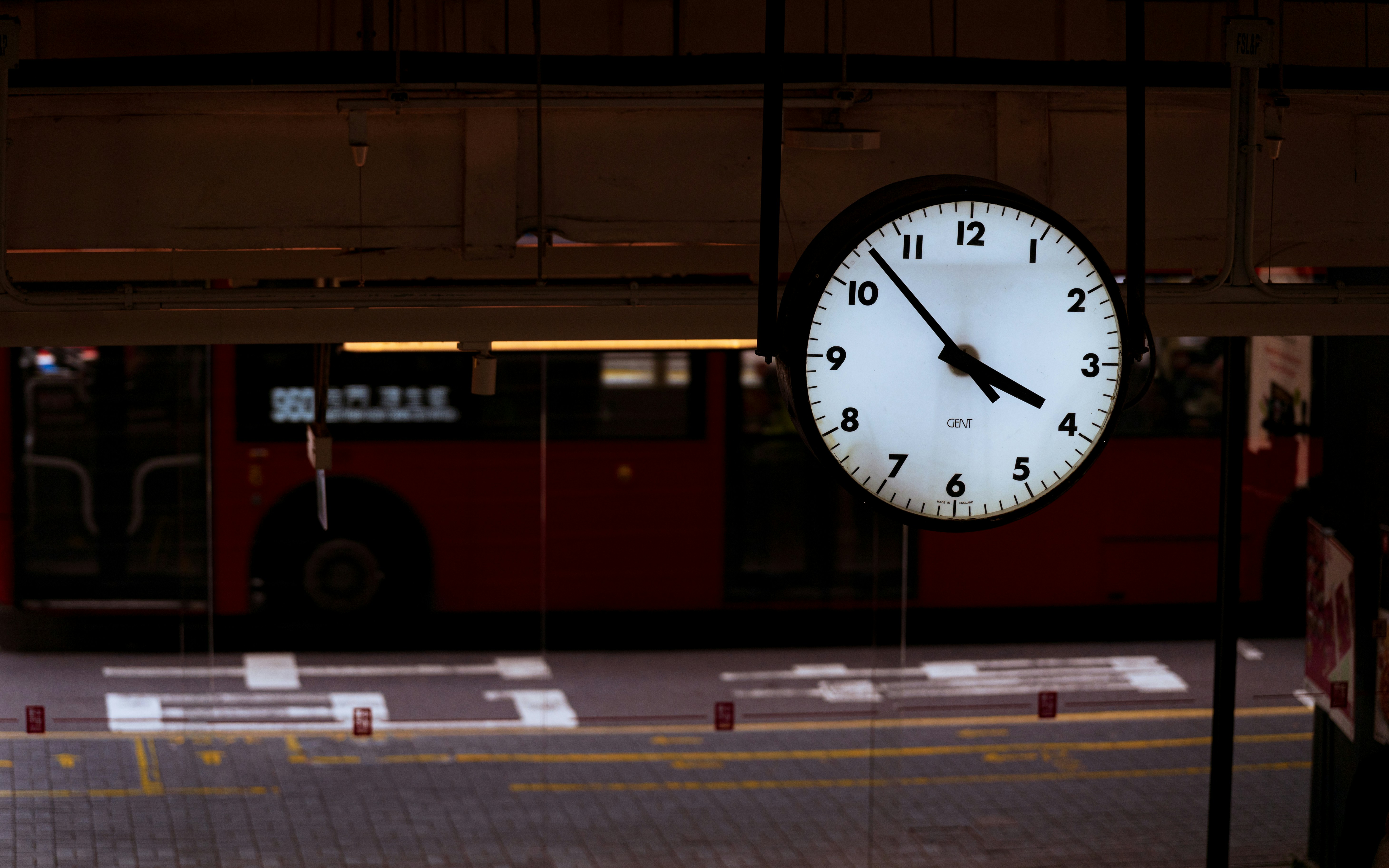 A clock shows 4:10 pm near a red bus.