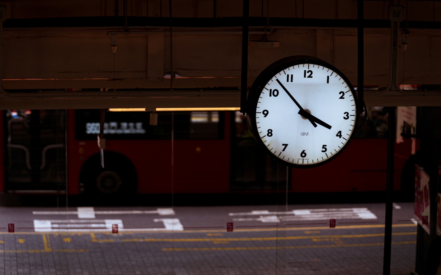 A clock shows 4:10 pm near a red bus.