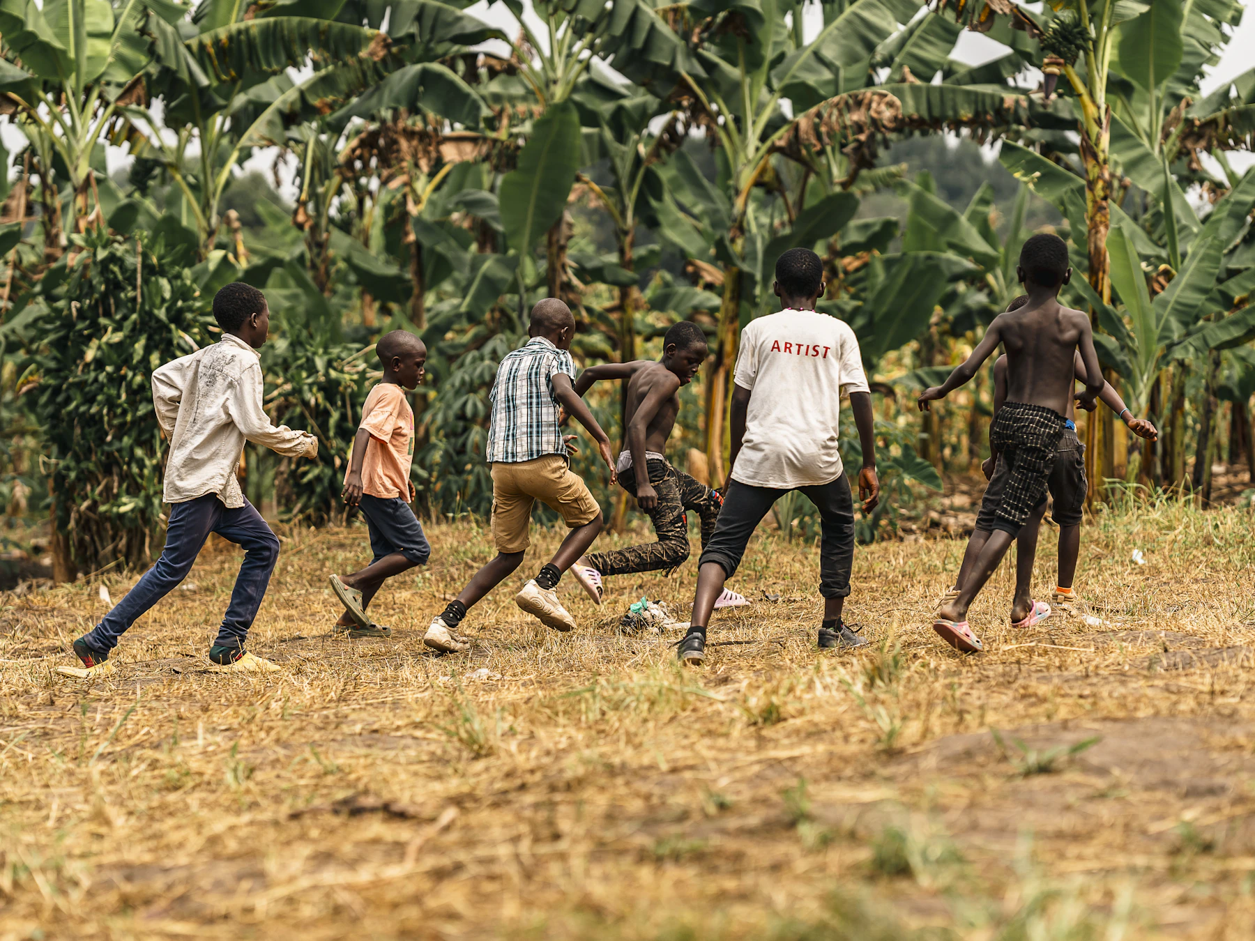Children running together while playing soccer outdoors on a sunny field