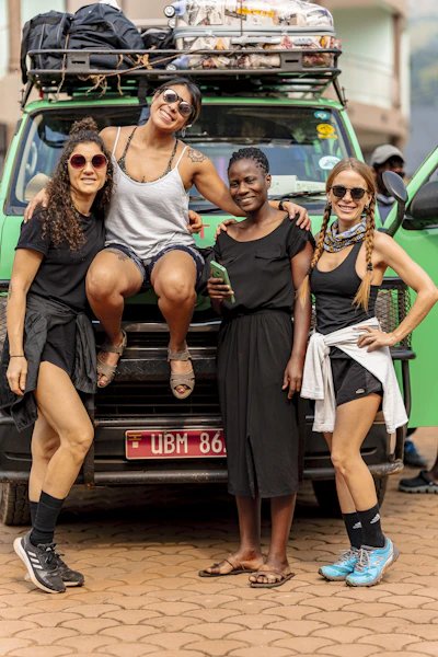 Four women posing in front of a green adventure van.
