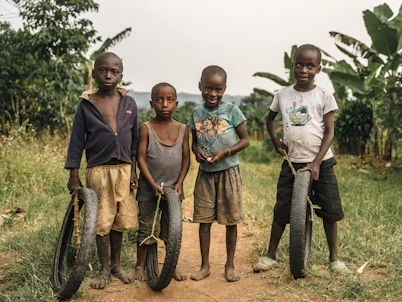 Four children stand with tires in a rural setting.