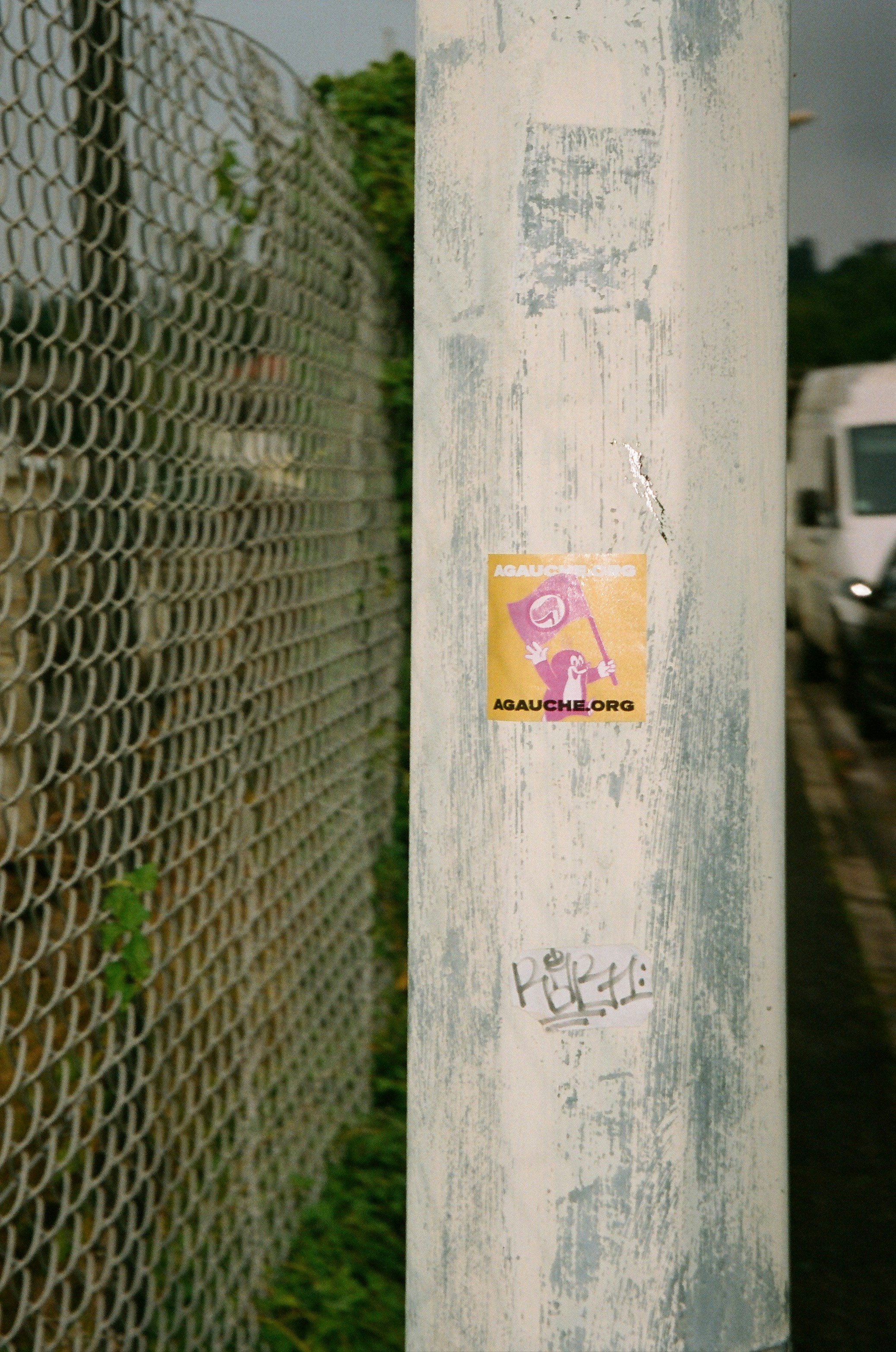 A sticker on a pole next to a fence.
