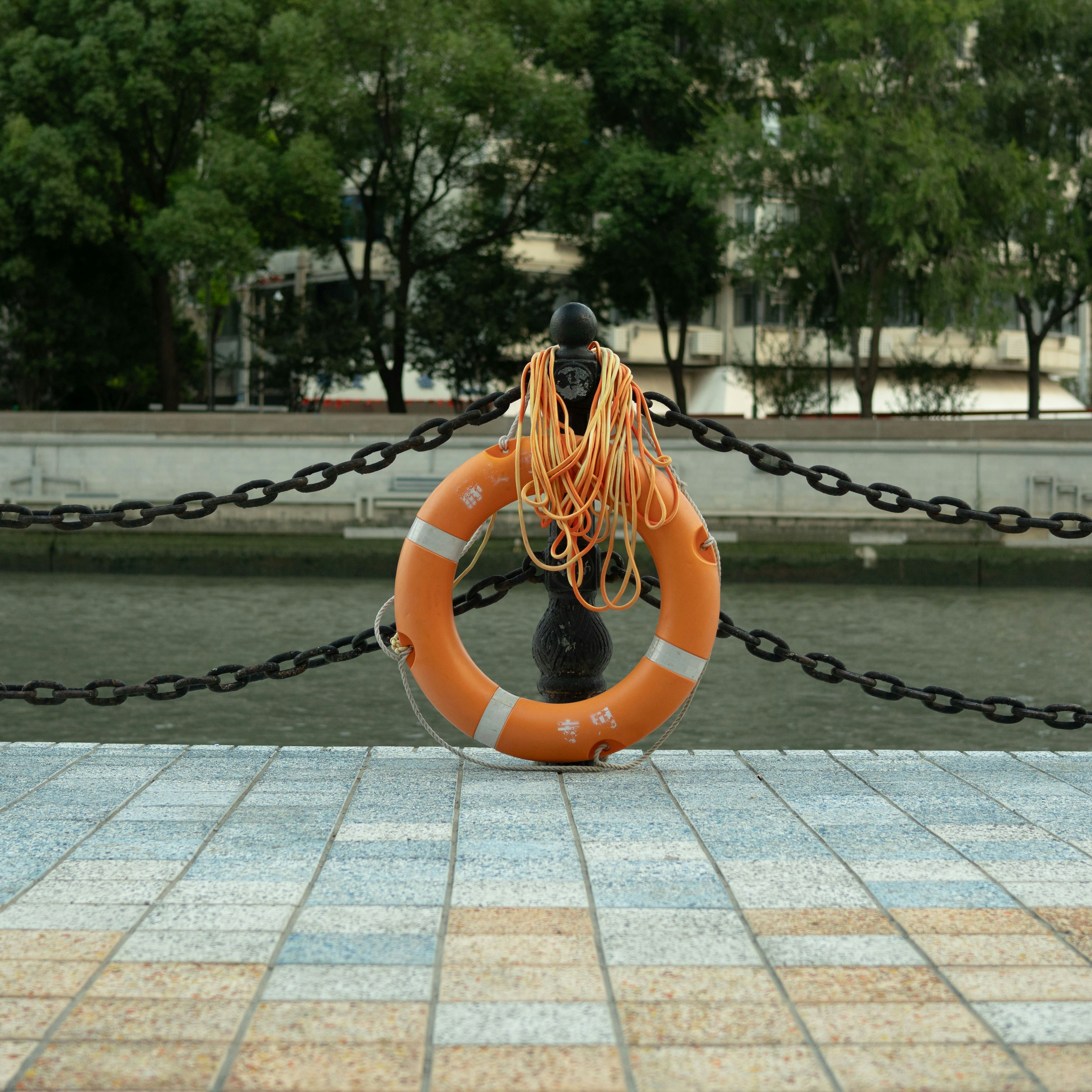 Orange life preserver with rope on a metal railing.