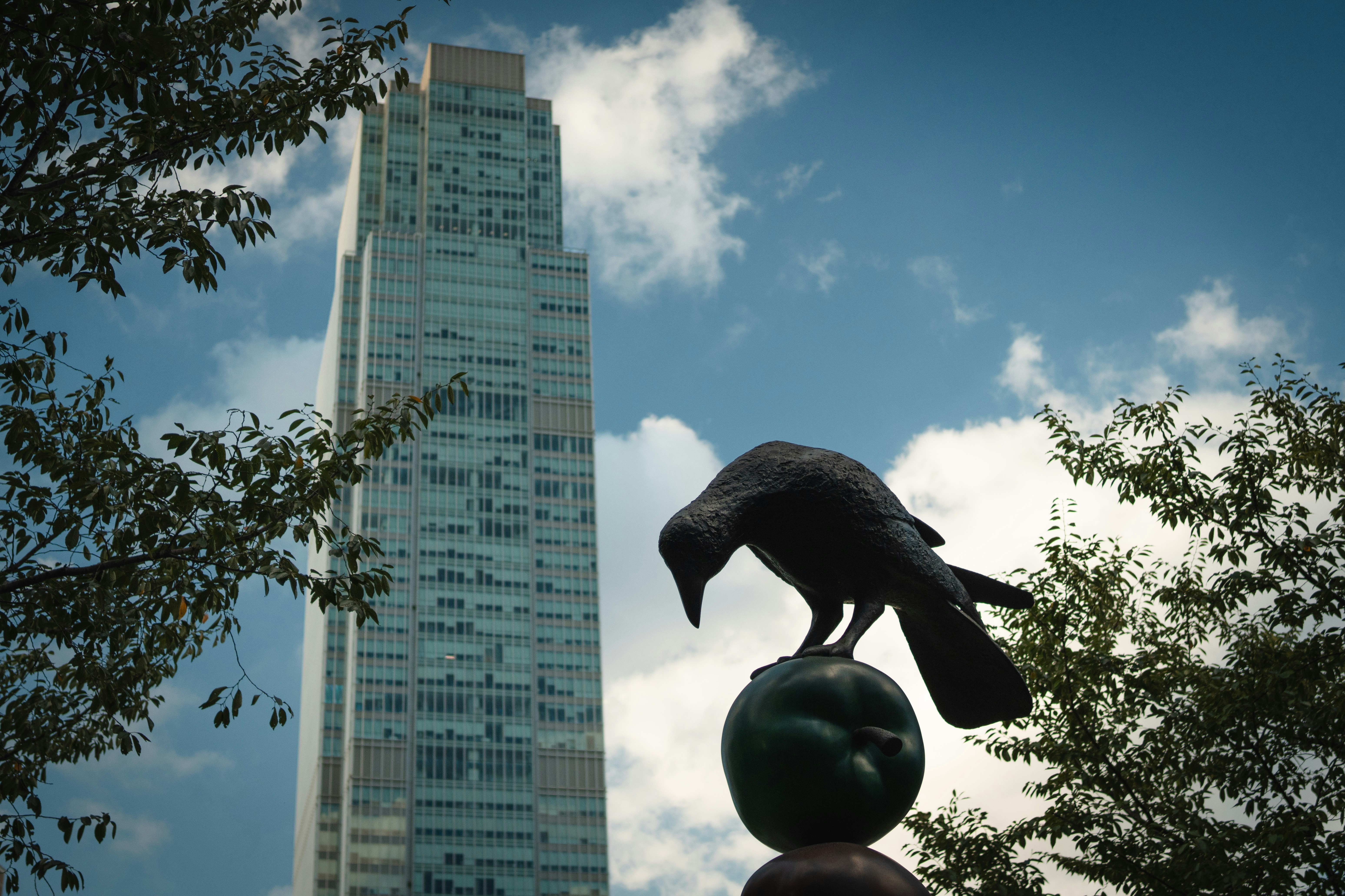 Crow statue on ball with skyscraper background