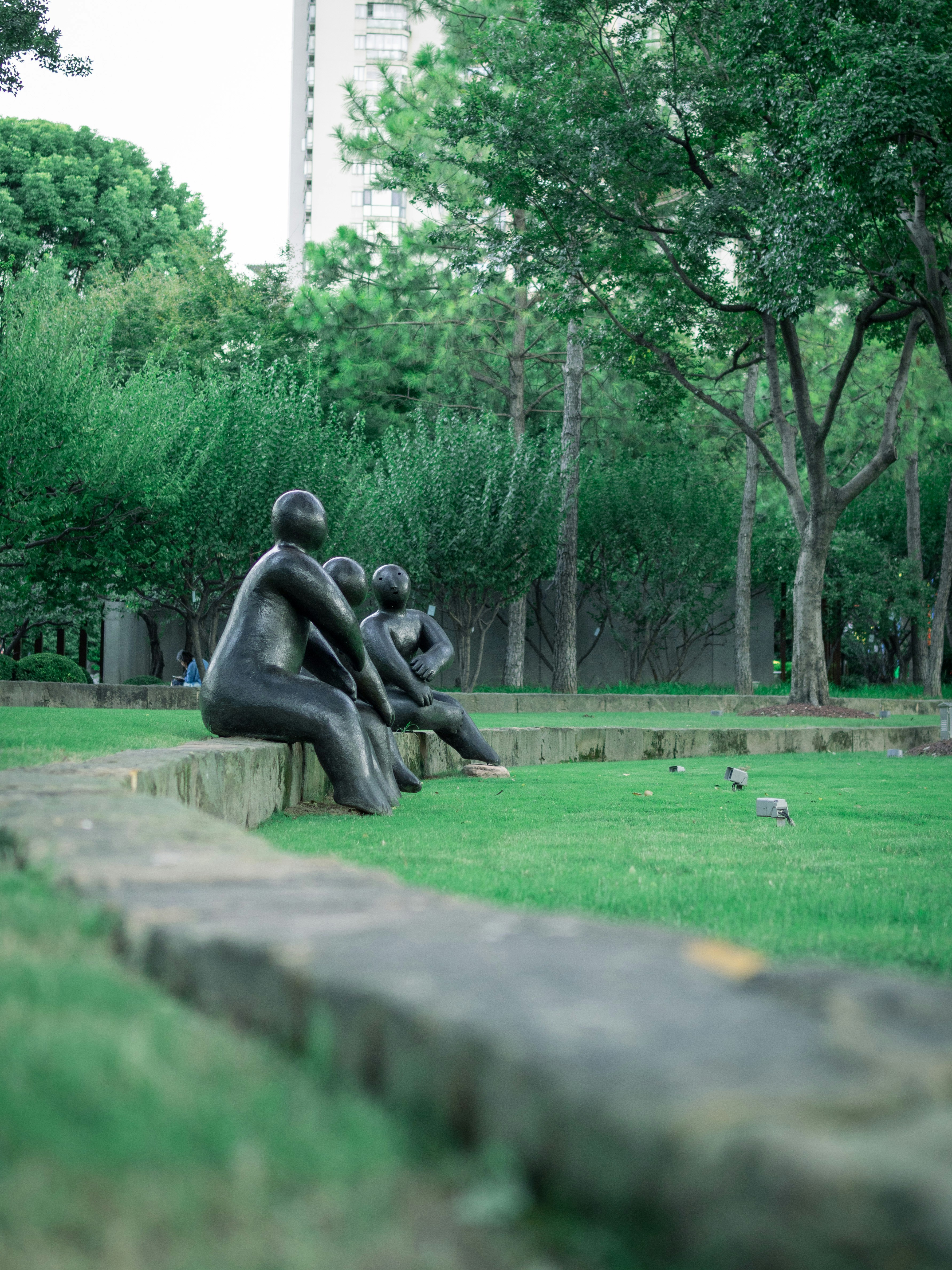 Sculptures of people sitting in a park.