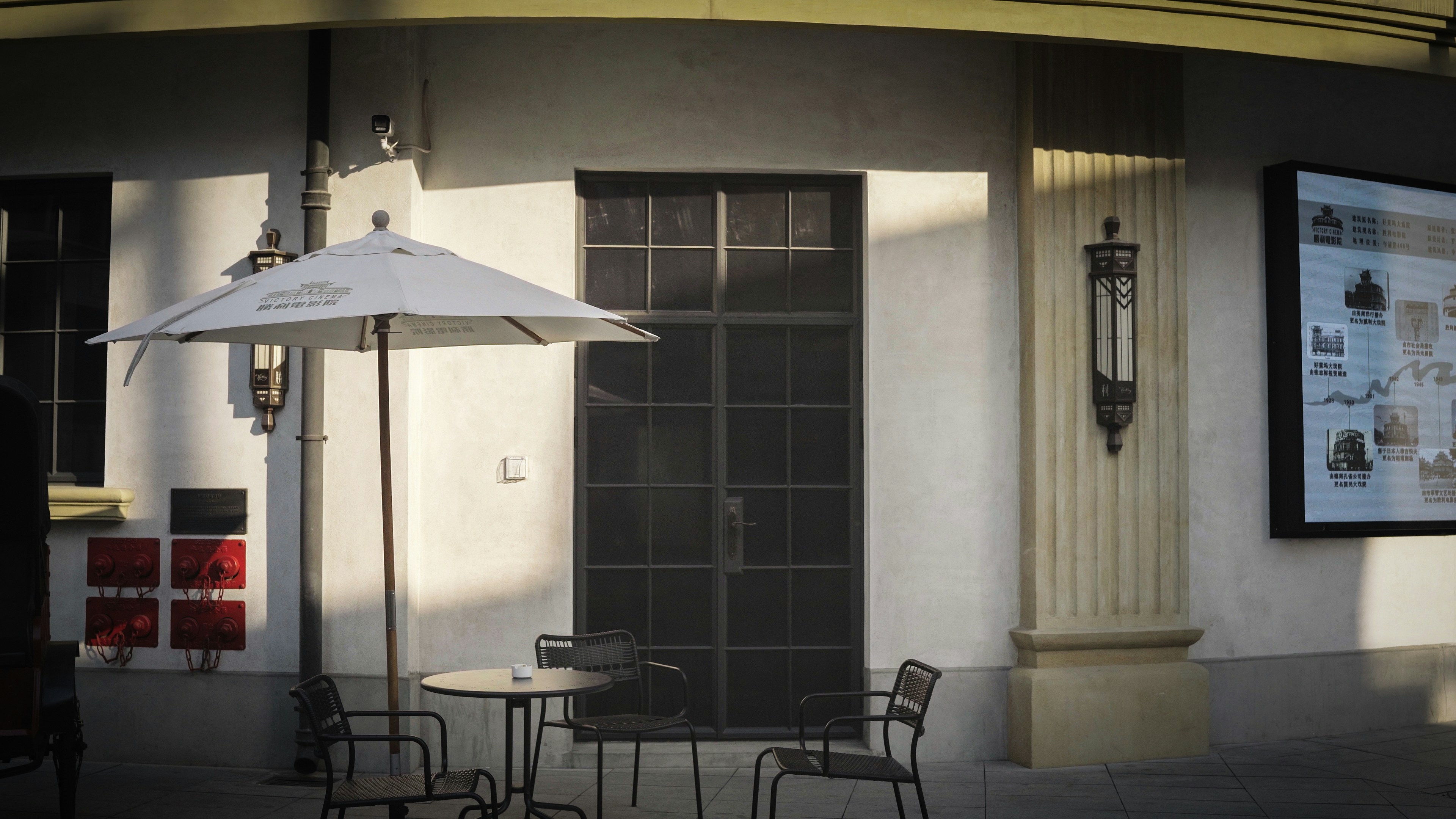 Sitzgelegenheiten im Café im Freien mit Sonnenschirm und Tischen.