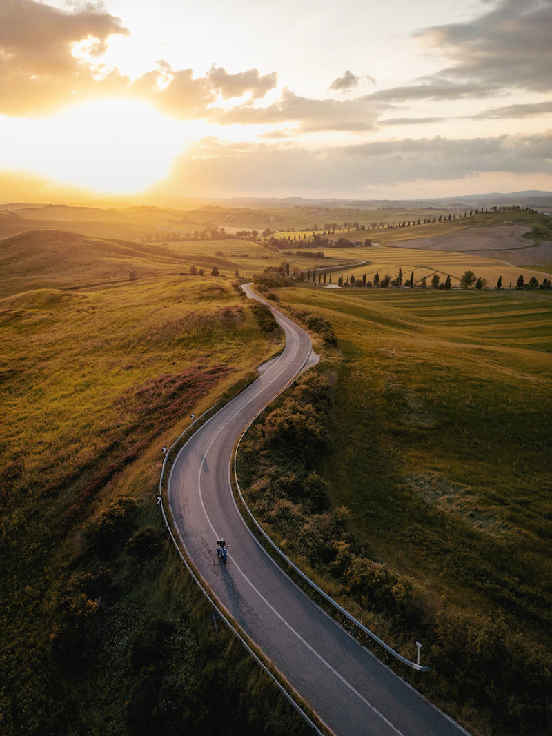 Curving road through rolling Tuscan hills at sunset