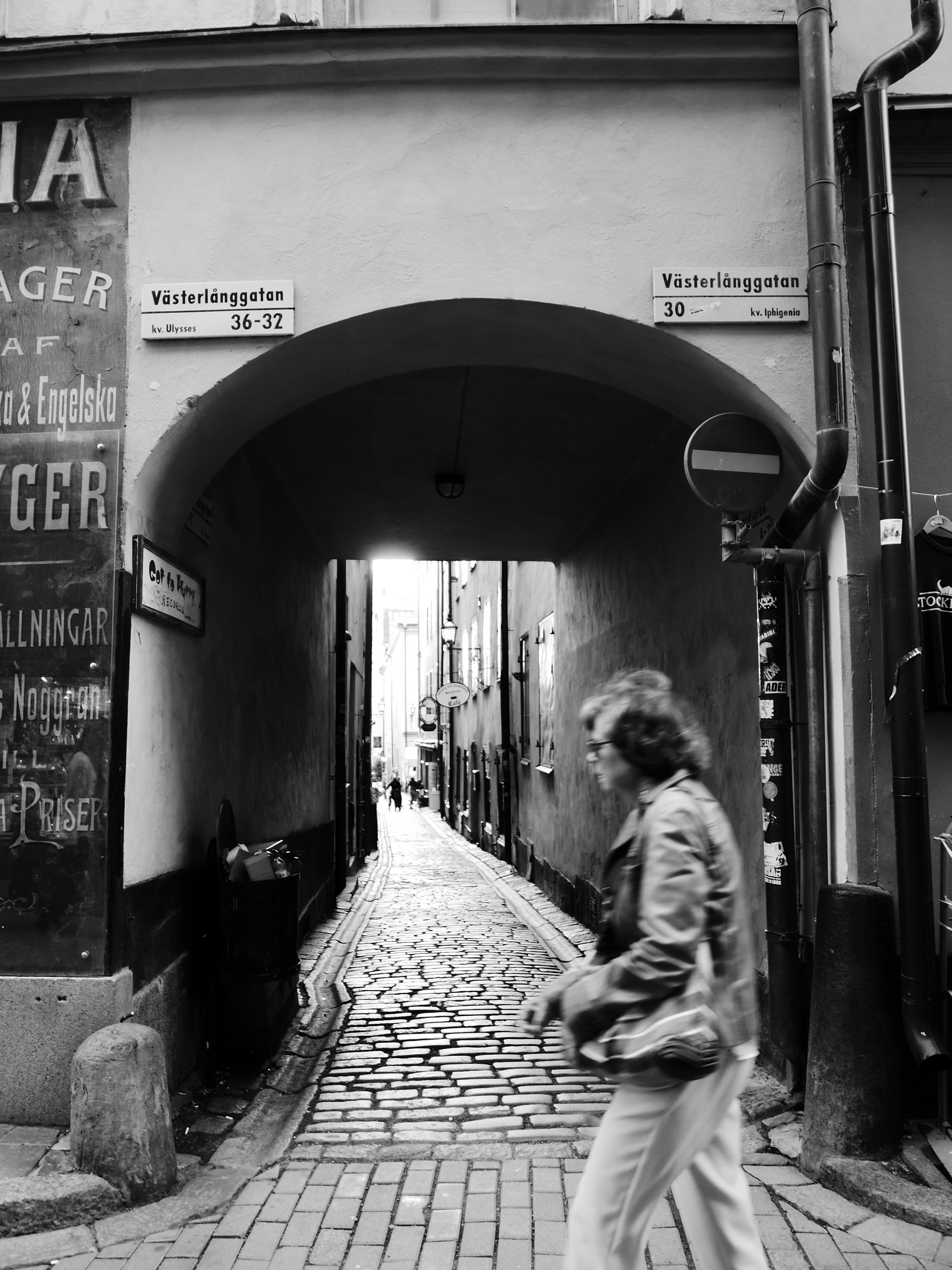 Person walking through narrow cobblestone alleyway.