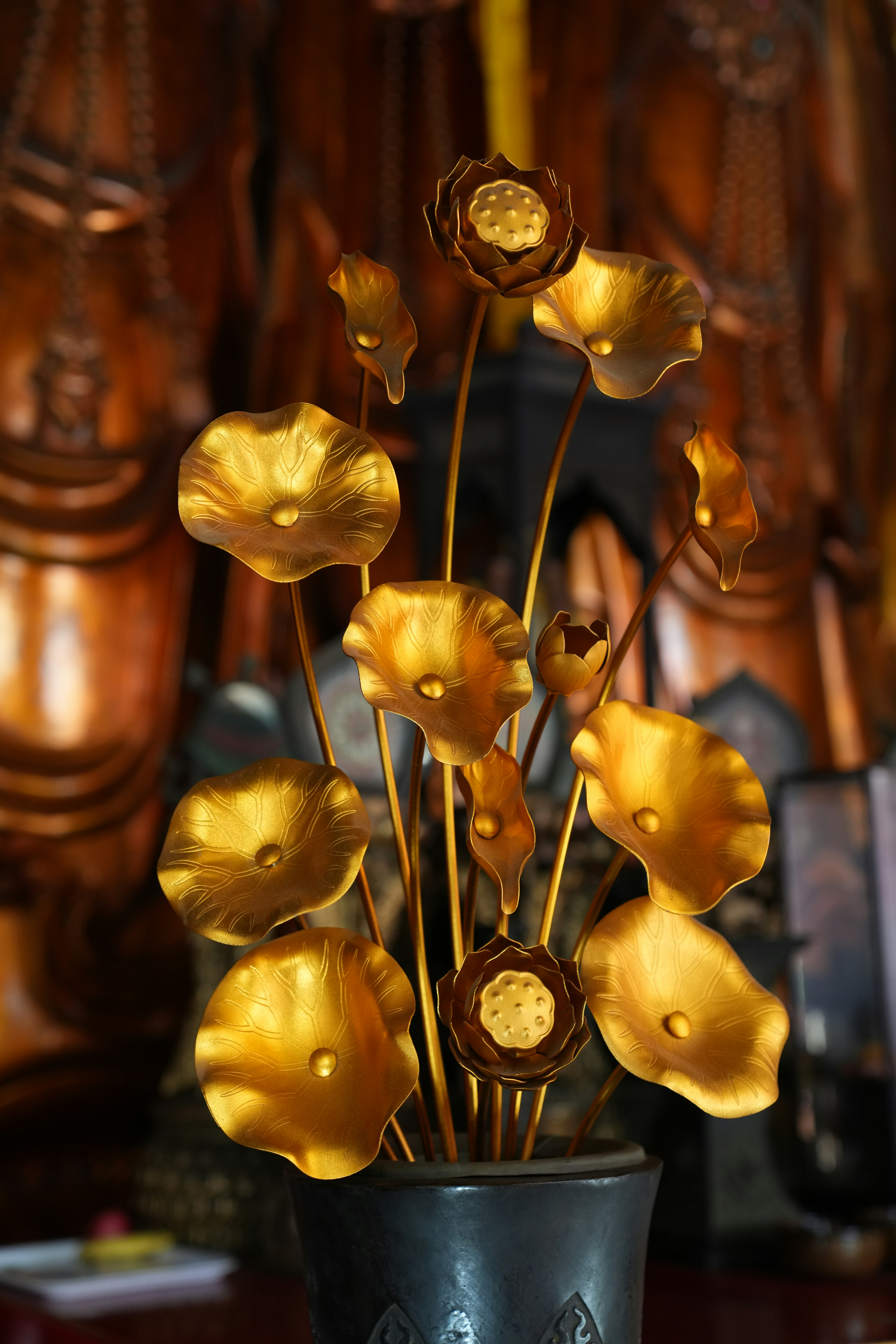 Golden lotus flowers in a dark vase