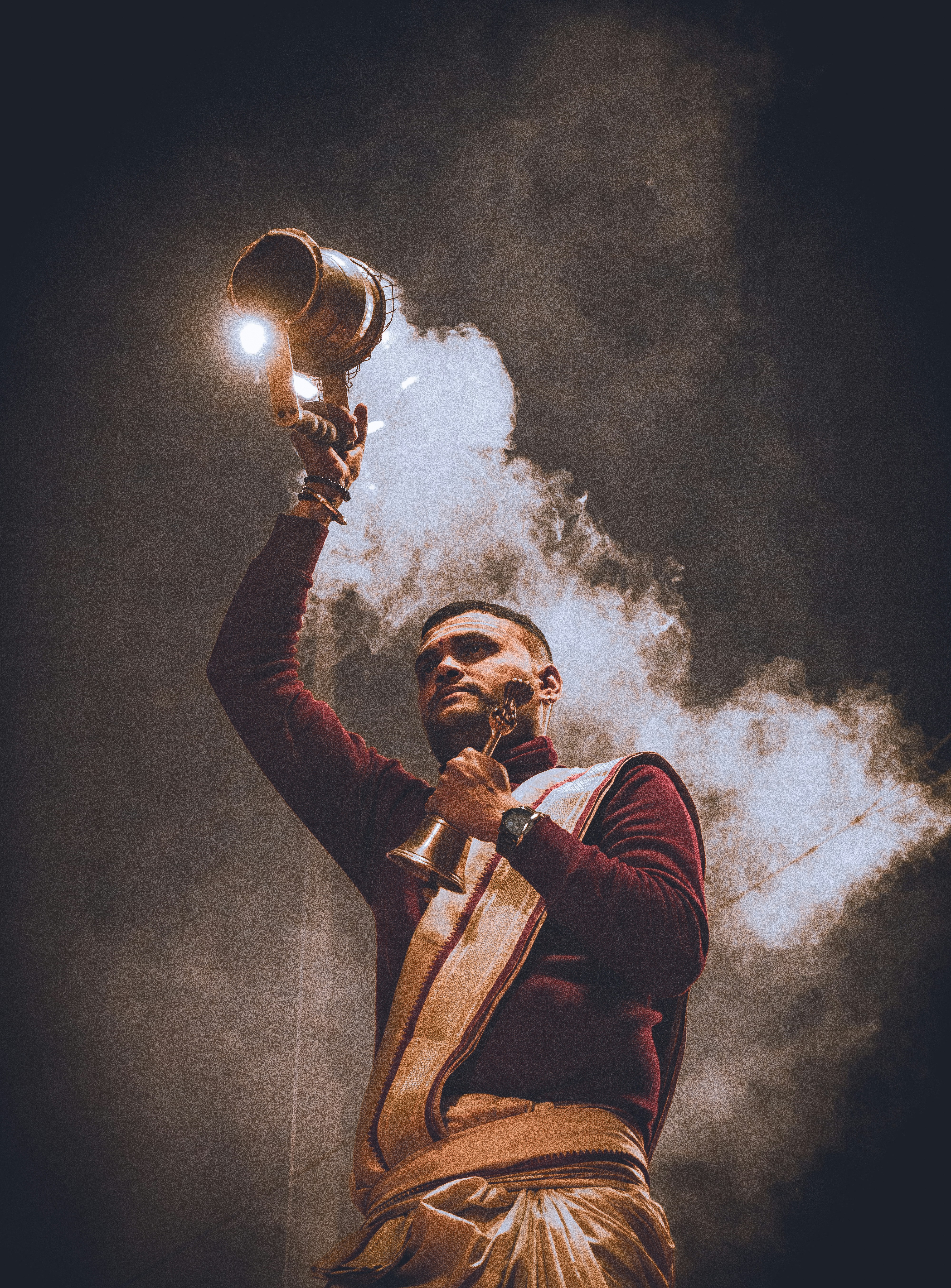 Man performing a ritual with smoke and bell.