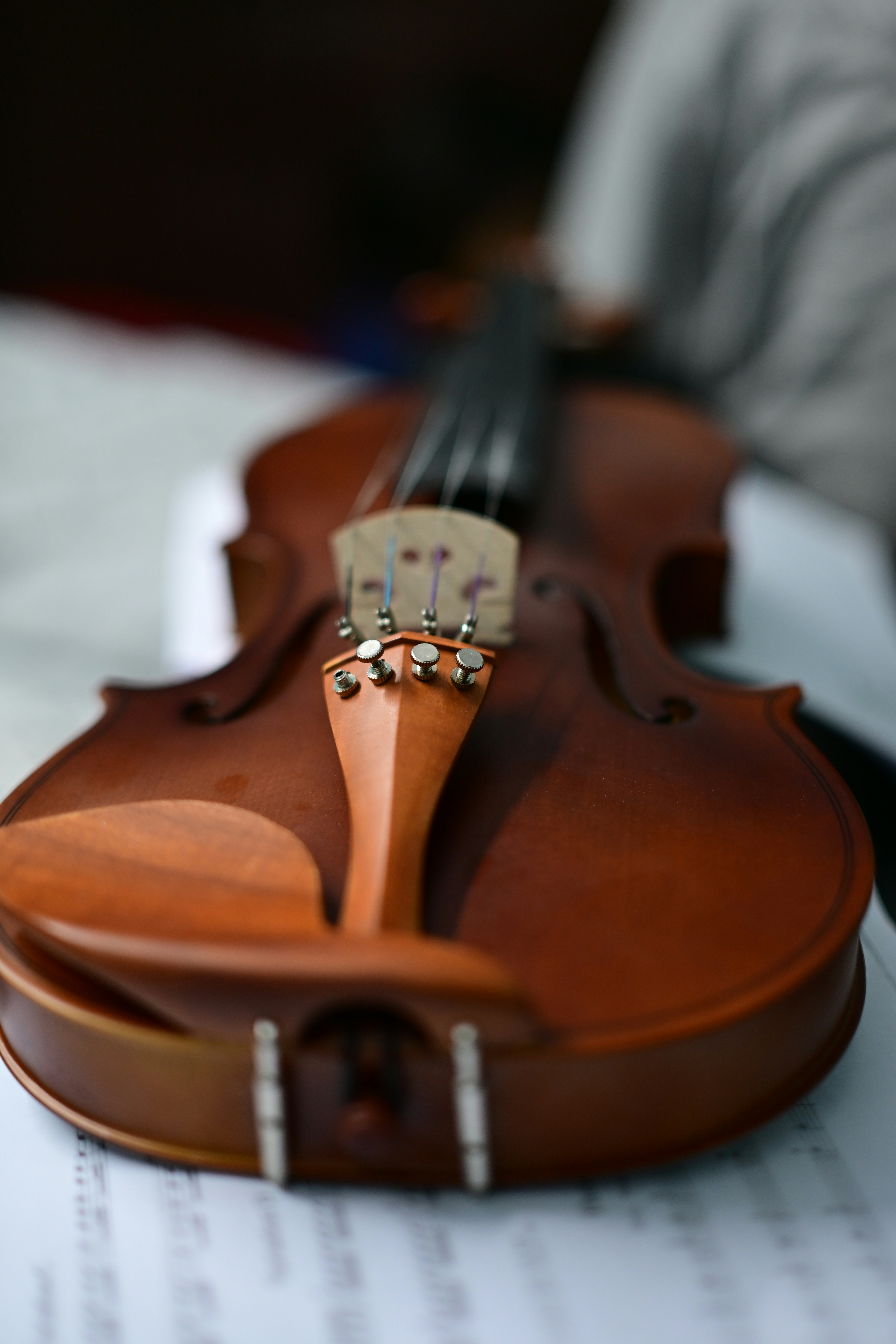 A close-up of a wooden violin resting on sheet music.