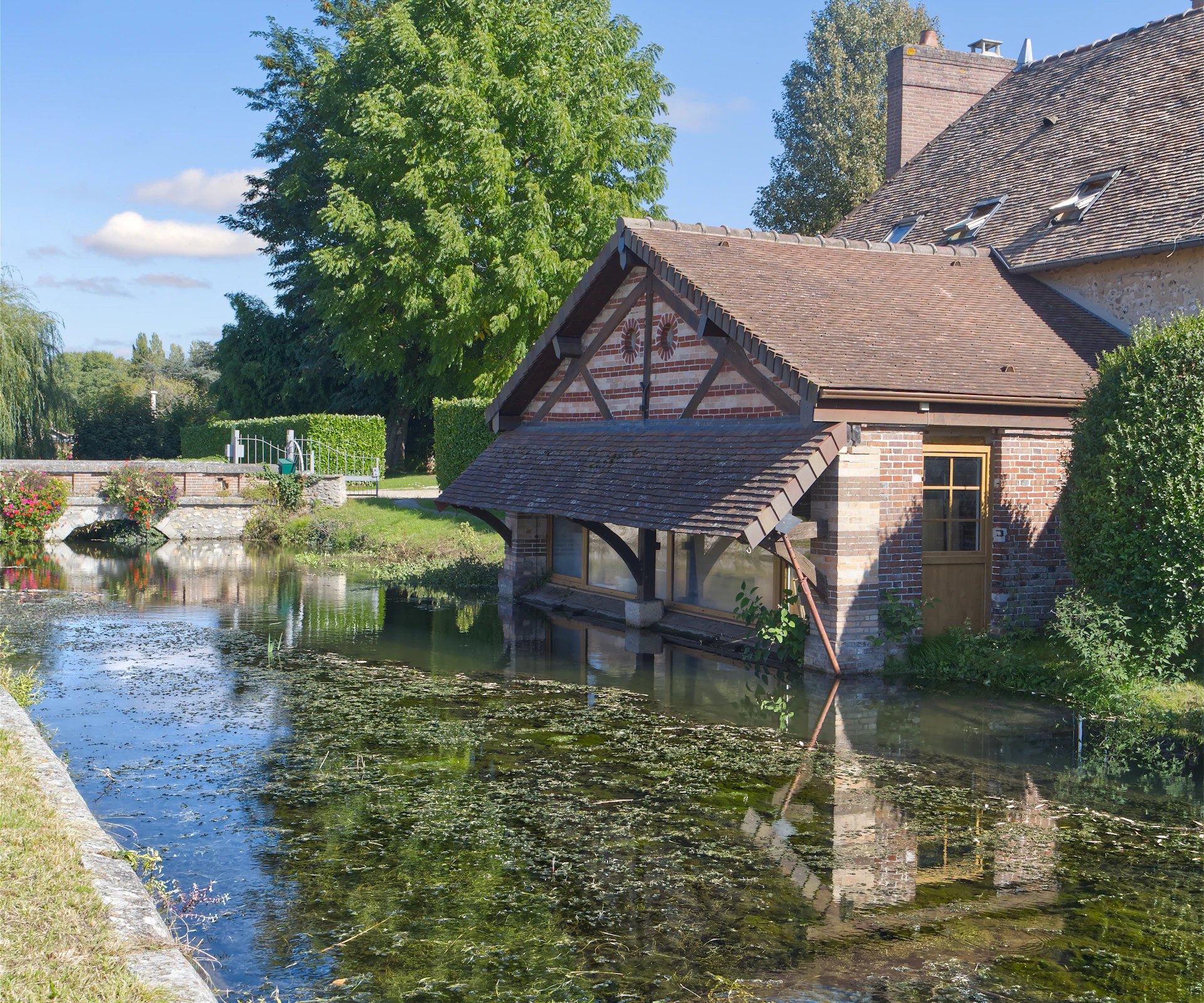 Old wash house by a calm river with reflections