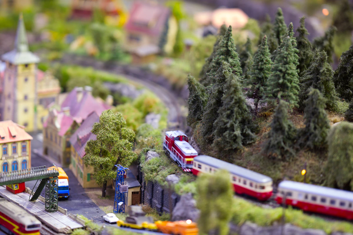 A miniature train traveling through a tiny village with model trees and buildings