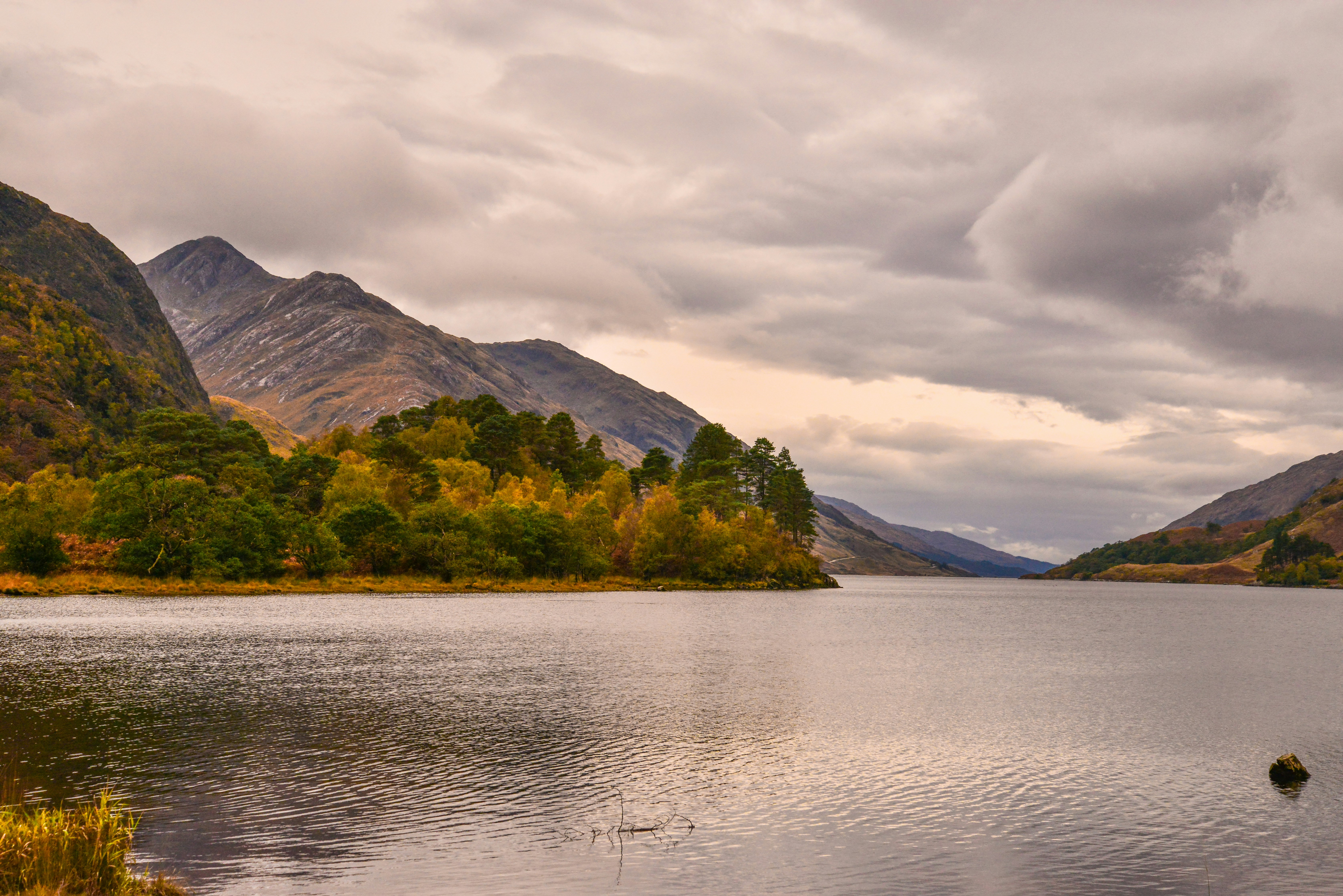 Lake and mountains with autumn trees under cloudy sky