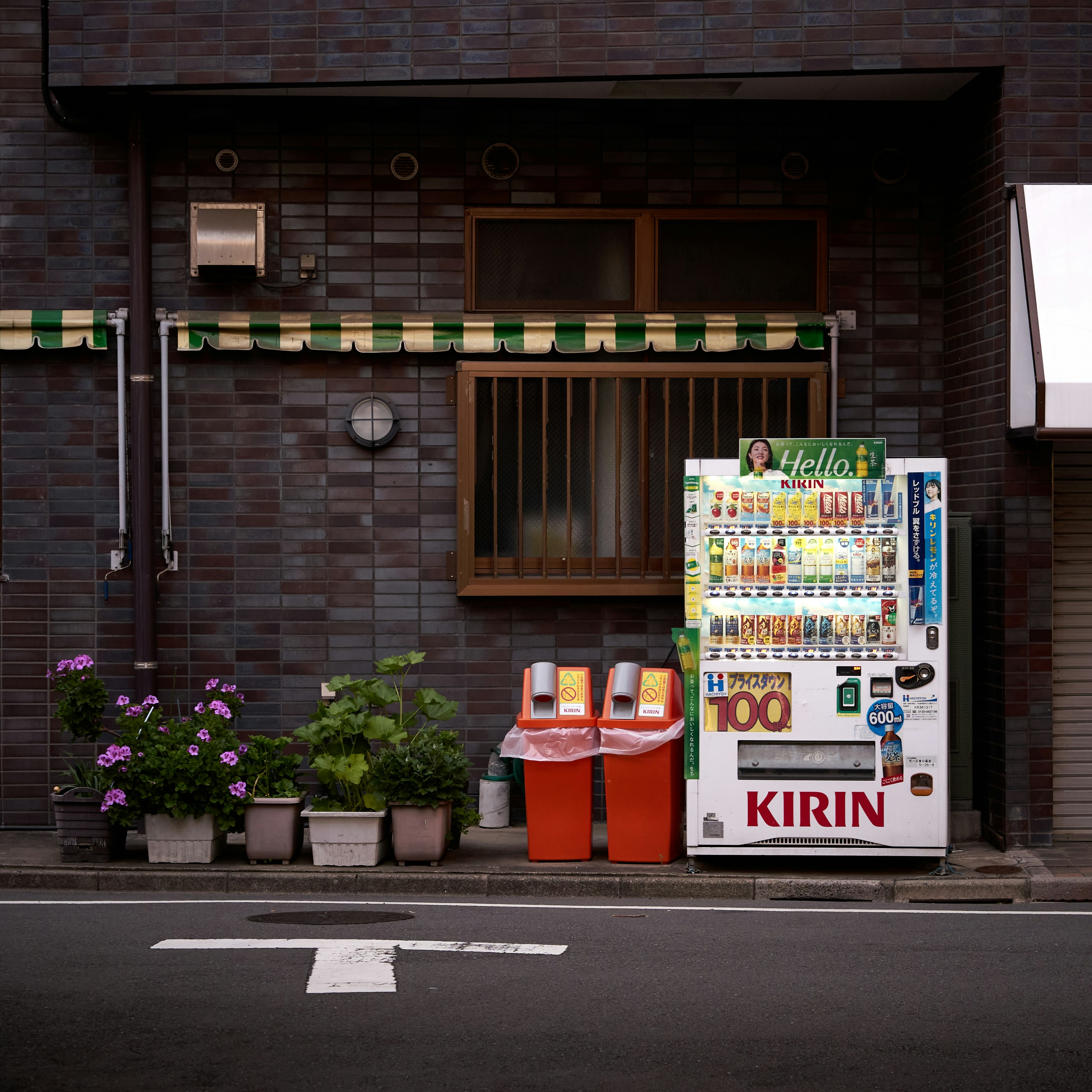 Vending machine and trash cans on city street.