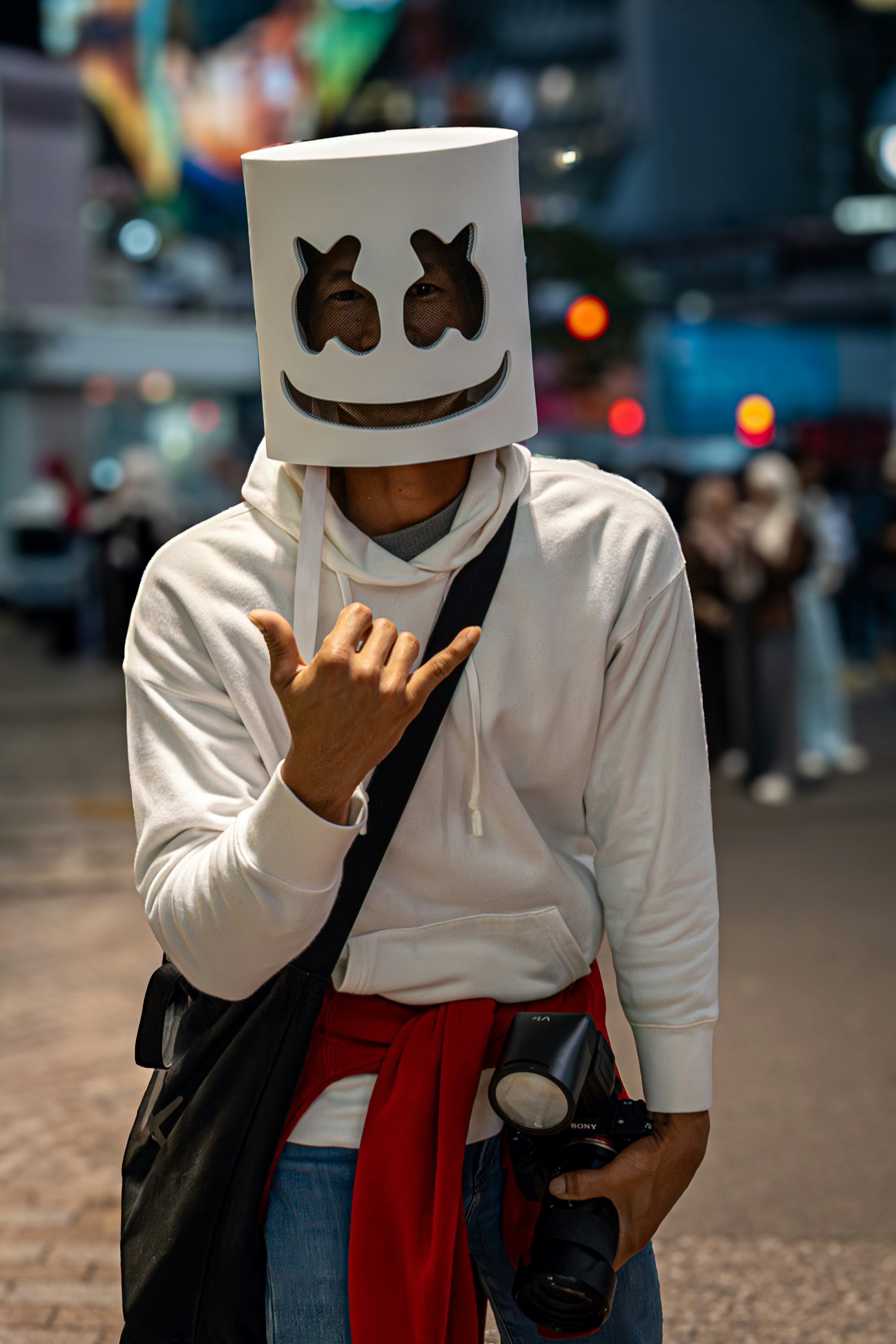 Person in marshmello mask holding camera and posing with camera.